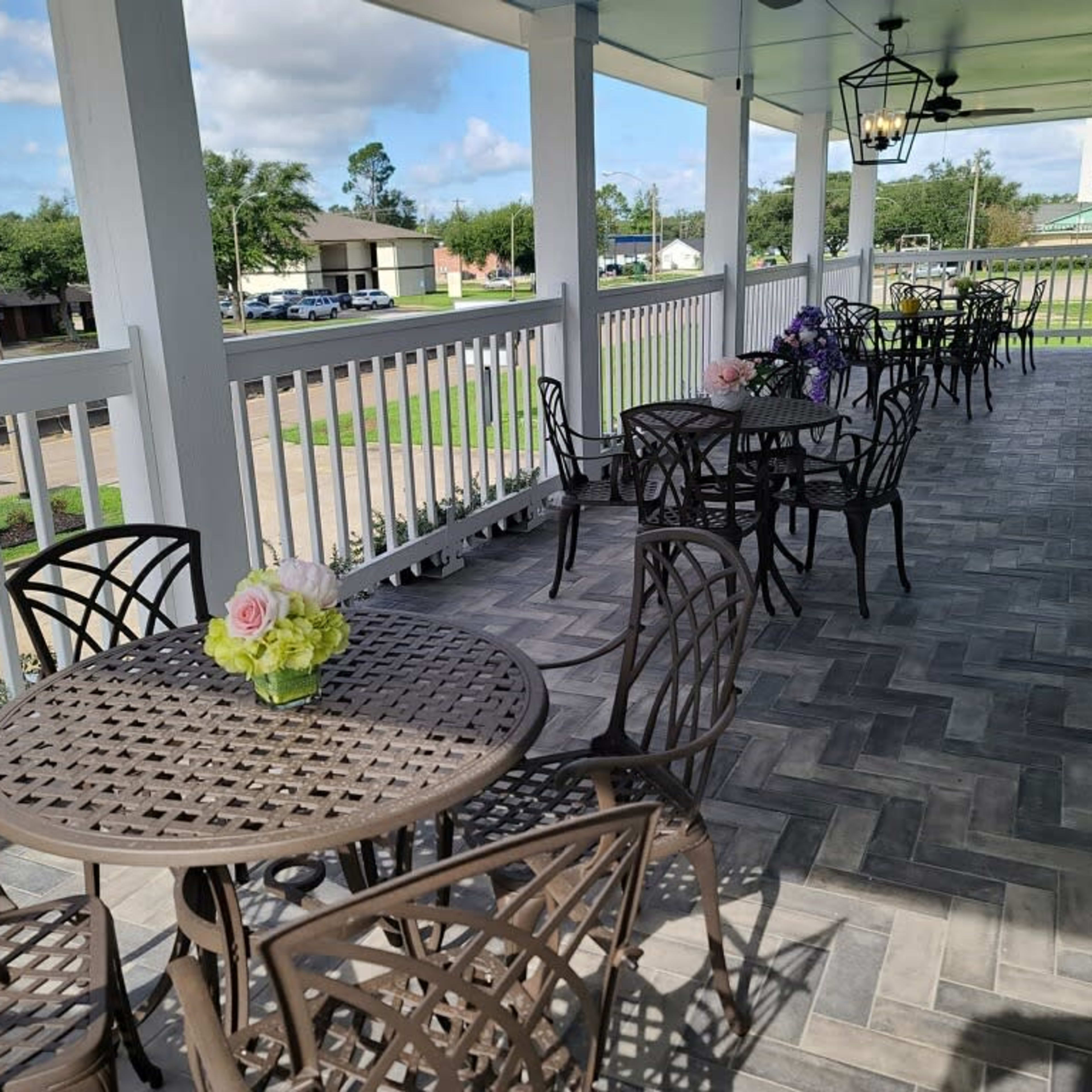 A patio area with several round tables and chairs, decorated with a flower arrangement.