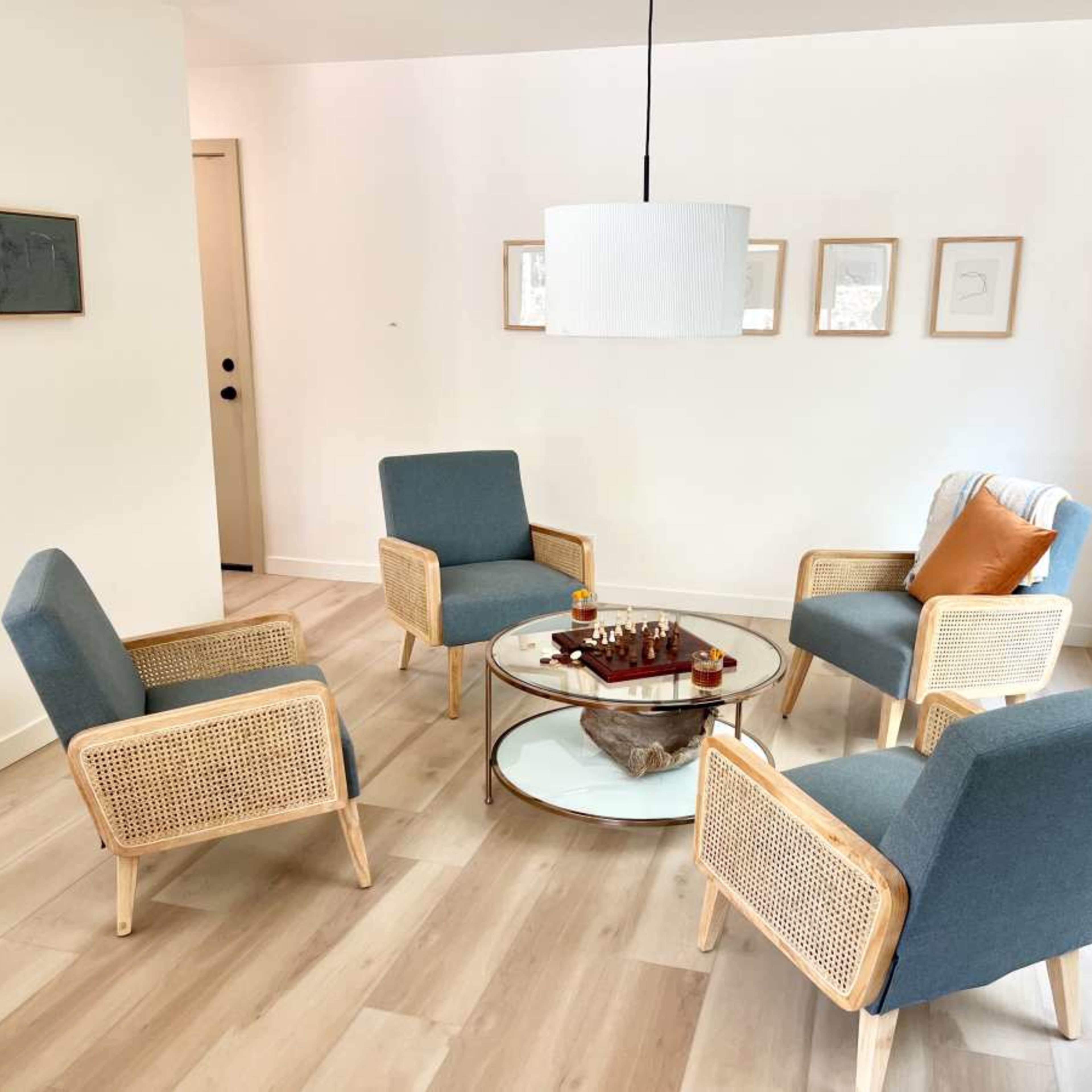 A modern seating area features four upholstered chairs arranged around a circular coffee table with a chess set on it.