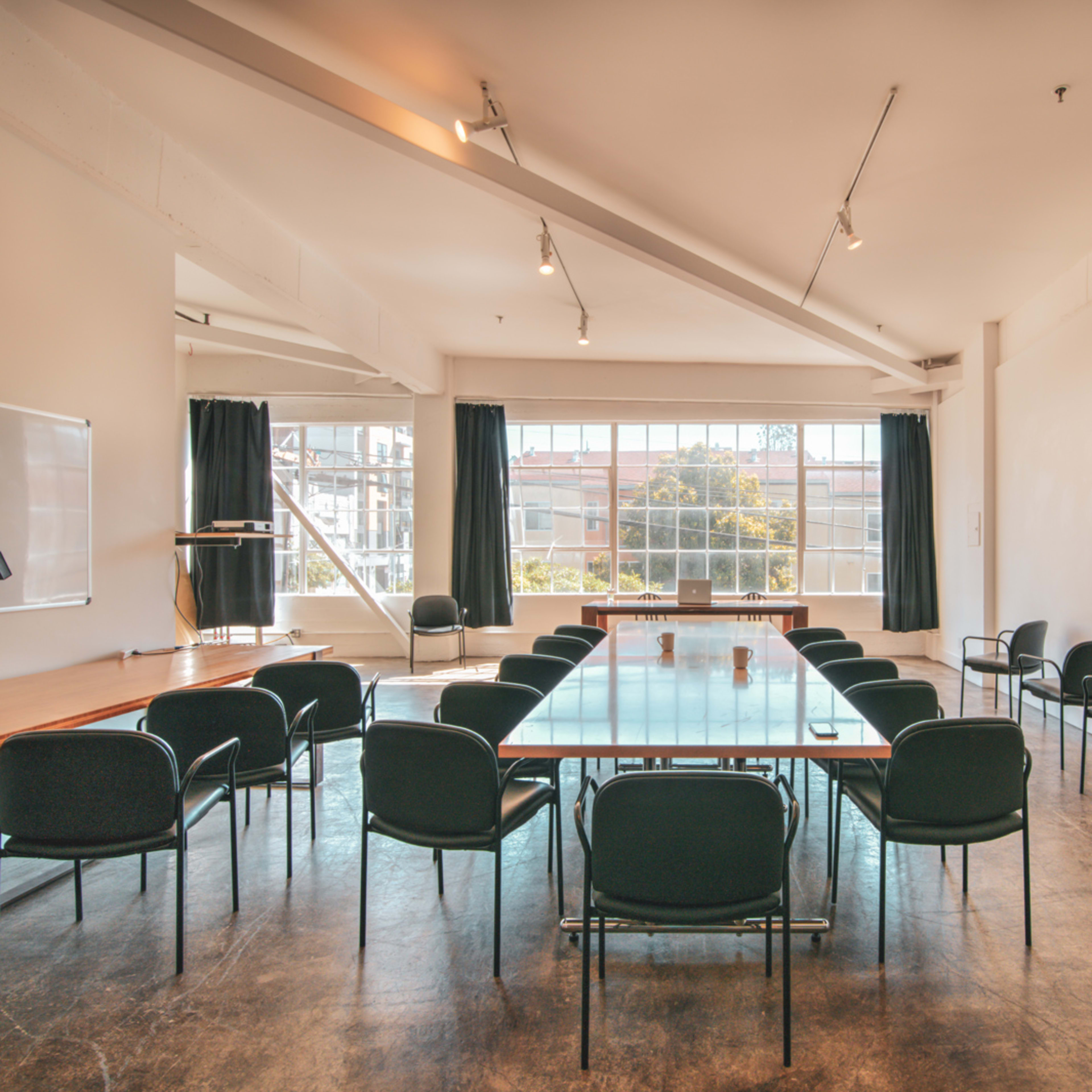 A large meeting room features a long table surrounded by chairs and a large window letting in natural light.