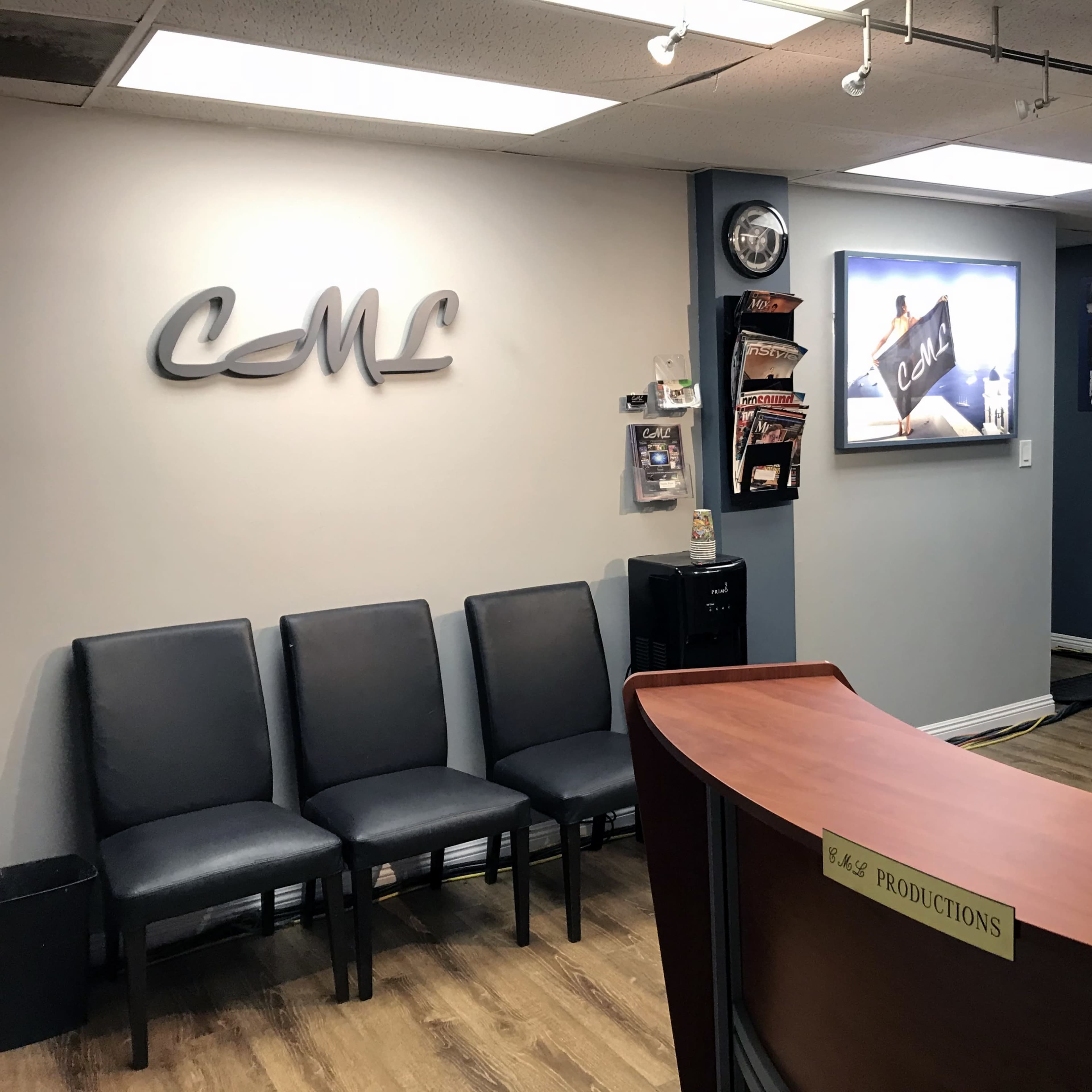 A reception area with a curved wooden desk, several black chairs arranged in a row, and wall-mounted displays featuring promotional materials and photographs.