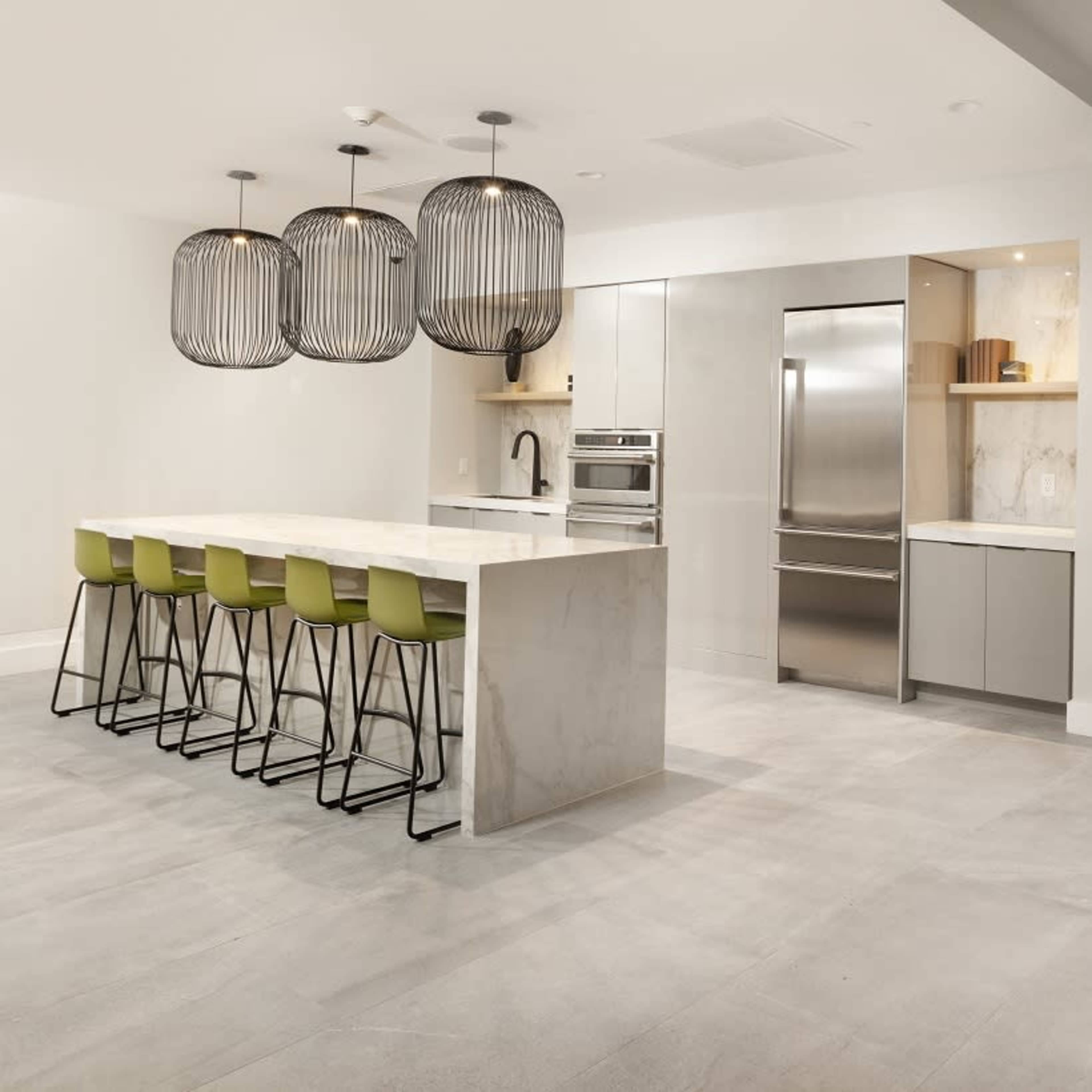 The modern kitchen features a large island with green bar stools, stainless steel appliances, and a cozy booth seating area against the wall.