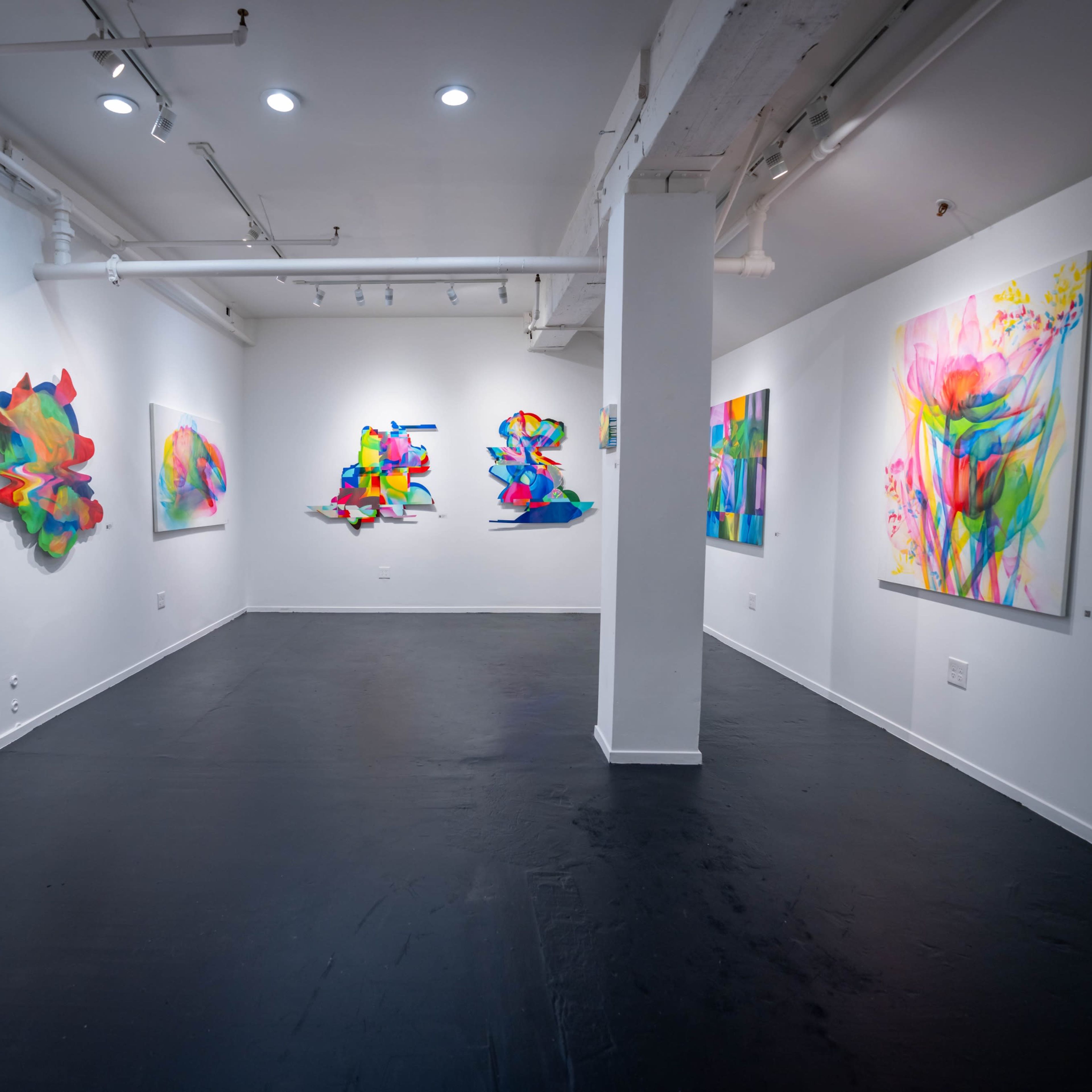 An art gallery with colorful abstract paintings and sculptures displayed on the white walls.