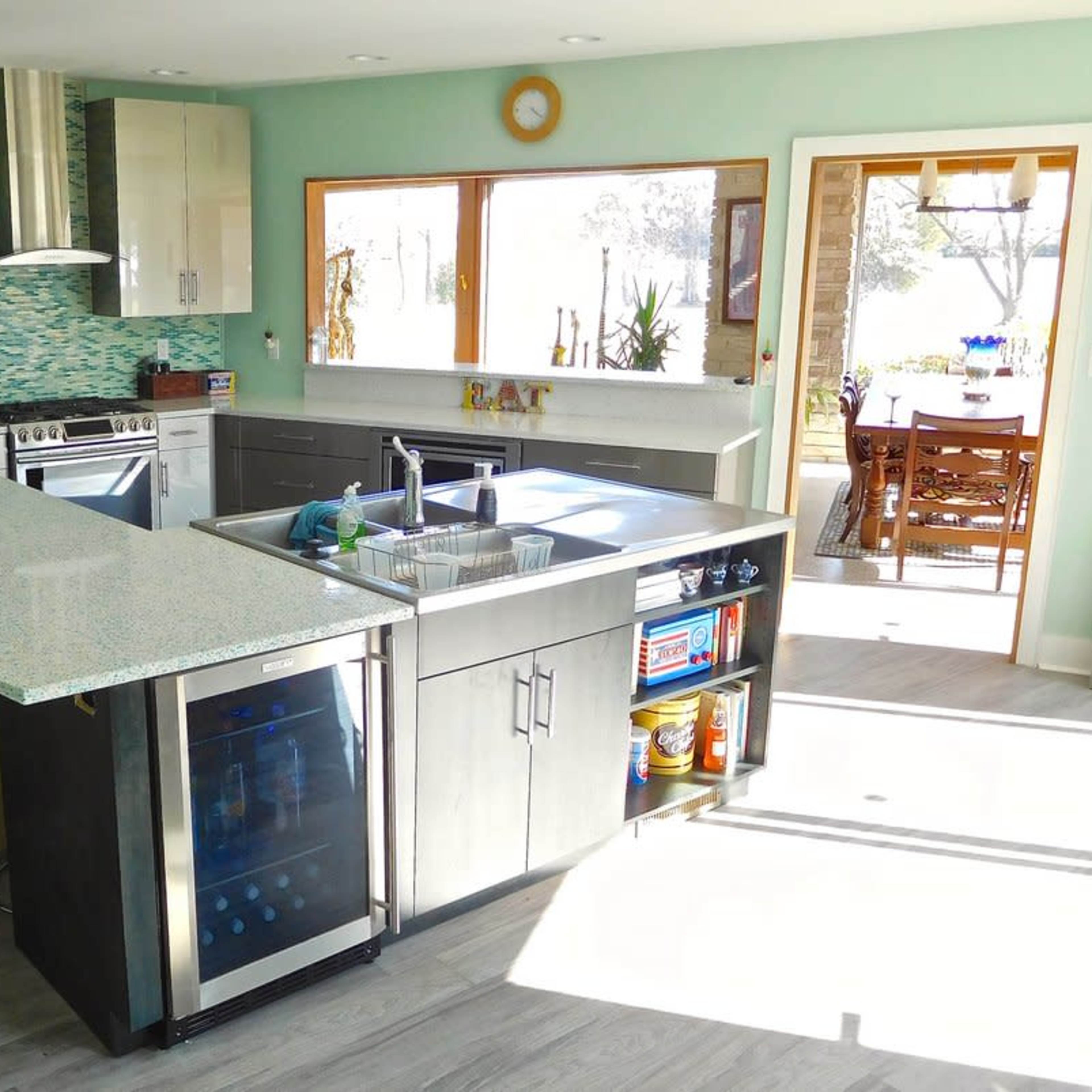 A modern kitchen featuring stainless steel appliances, a large island with seating, and a window that opens to a dining area.
