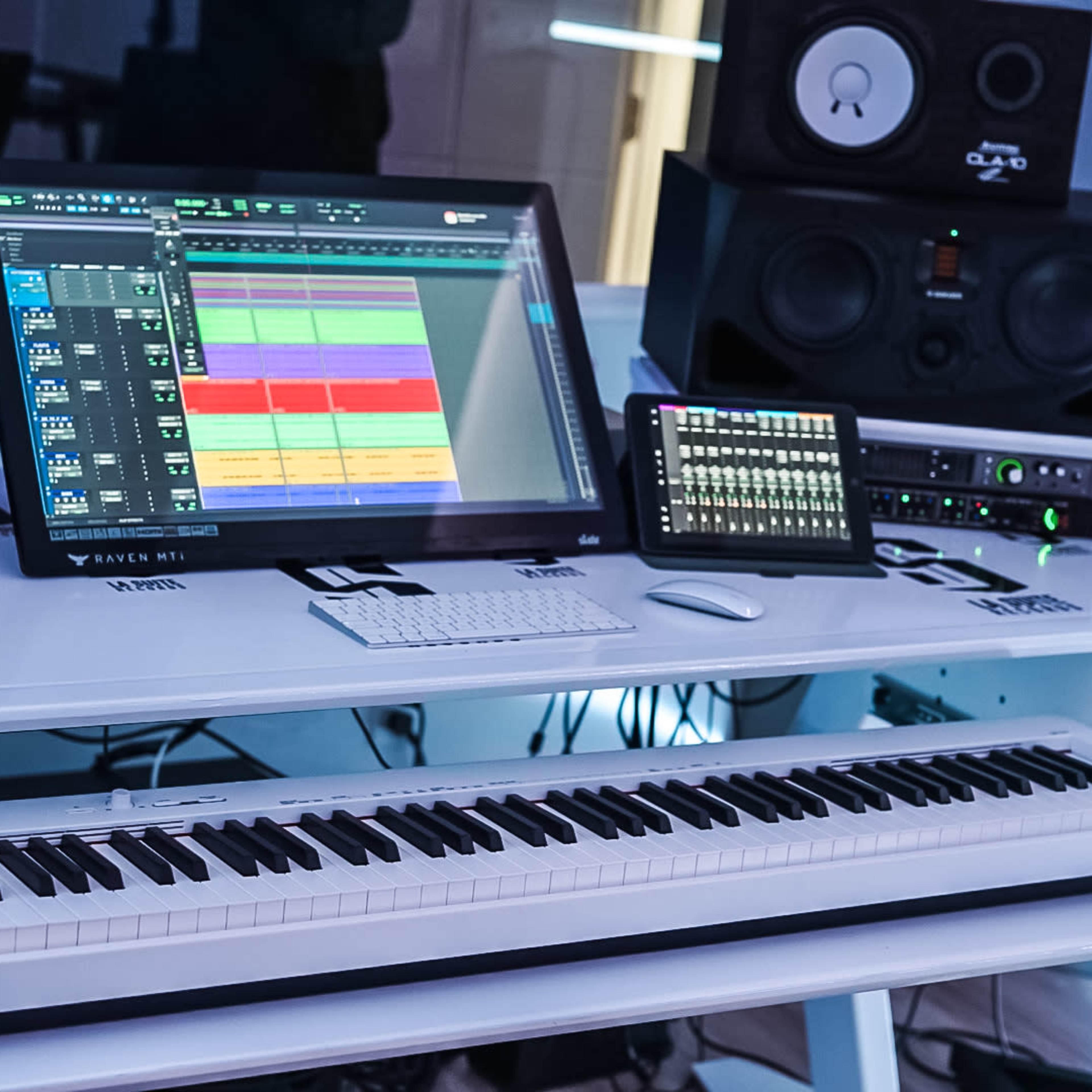 A modern music production studio featuring a computer with digital audio workstation software, a keyboard, and studio monitors.
