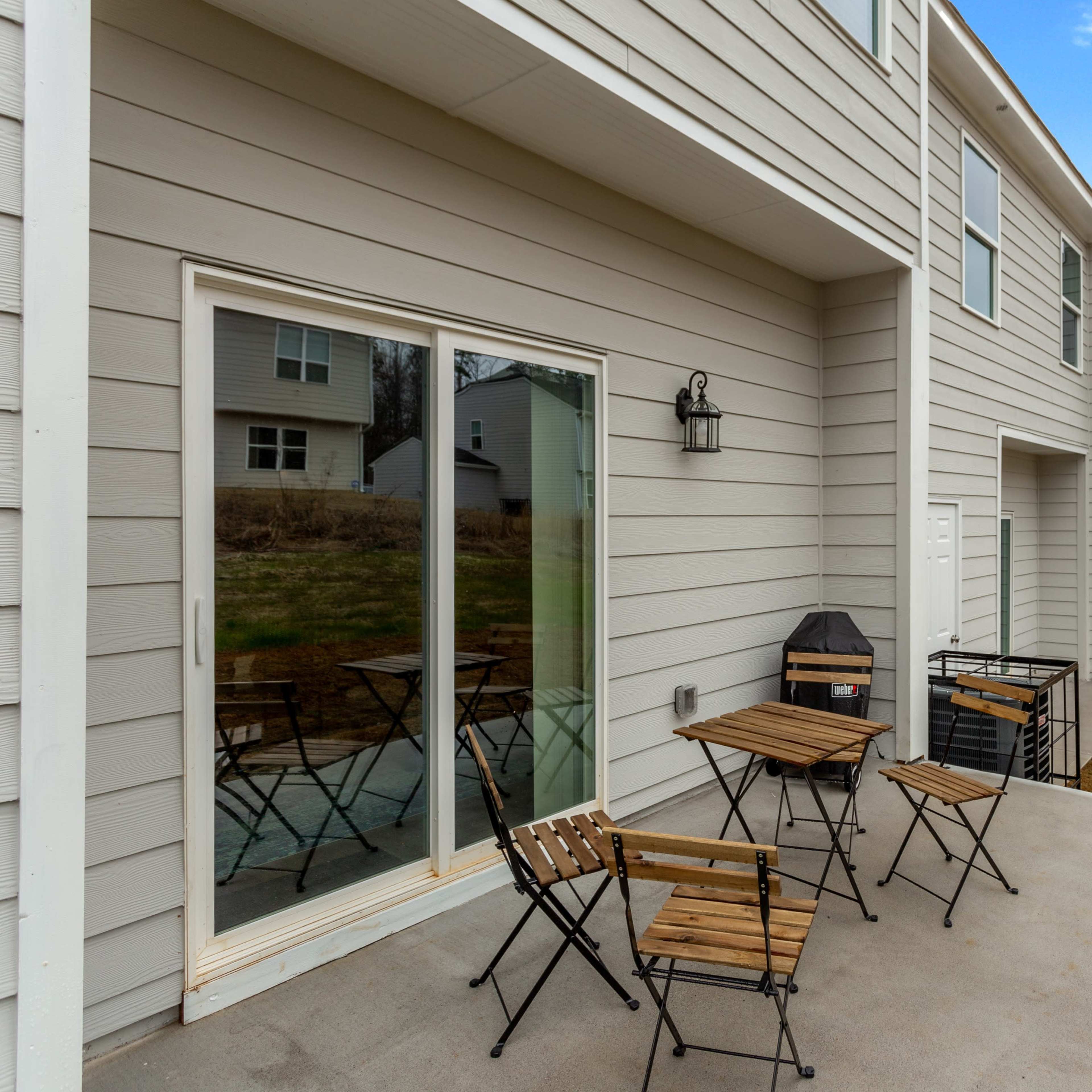A row of townhouses with a patio area featuring four small wooden tables and chairs.