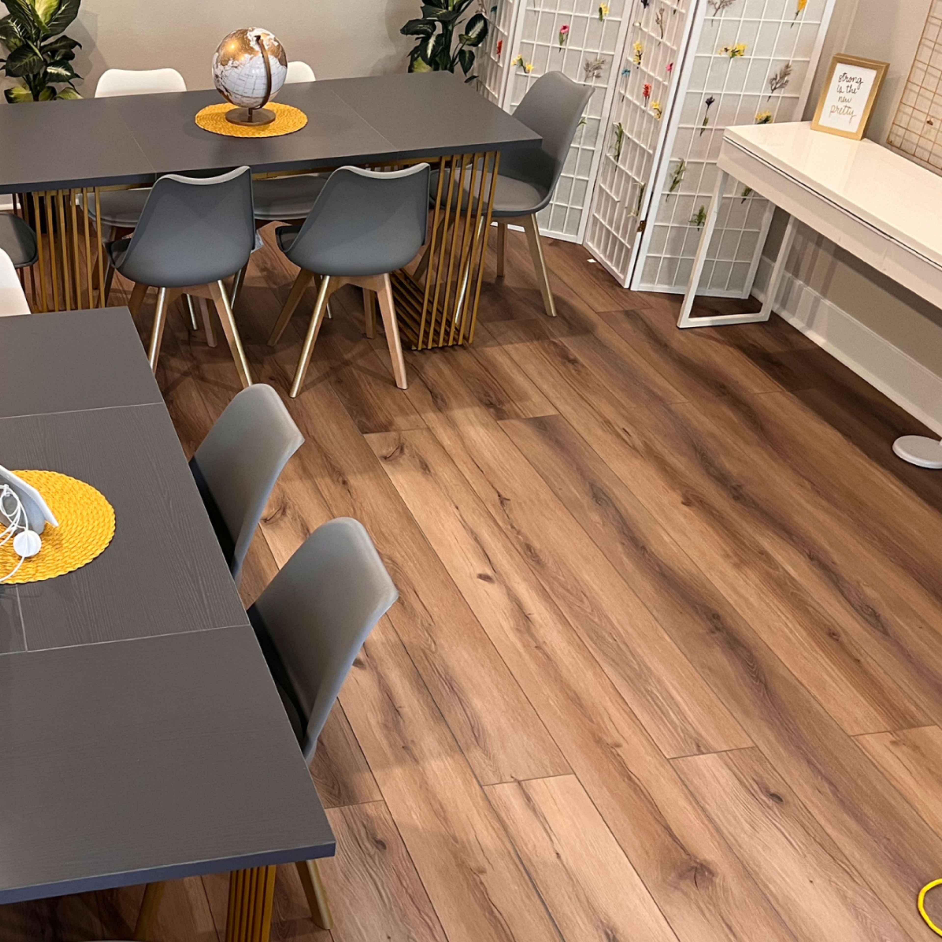 The scene features a modern dining area with two tables, each set with decorative centerpieces, surrounded by chairs and showcasing wooden flooring.