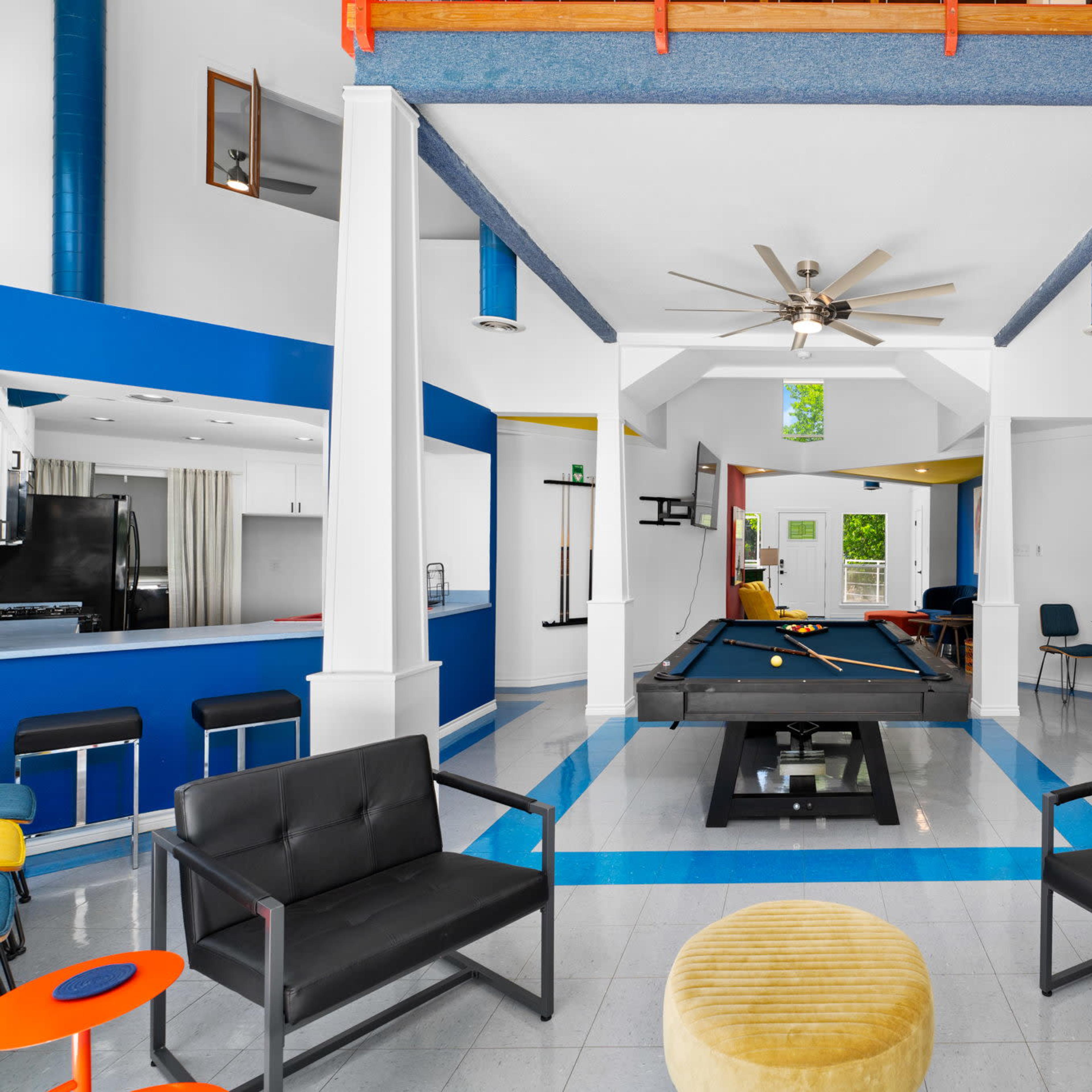 A vibrant game room featuring a pool table at its center, surrounded by stylish seating and modern decor.