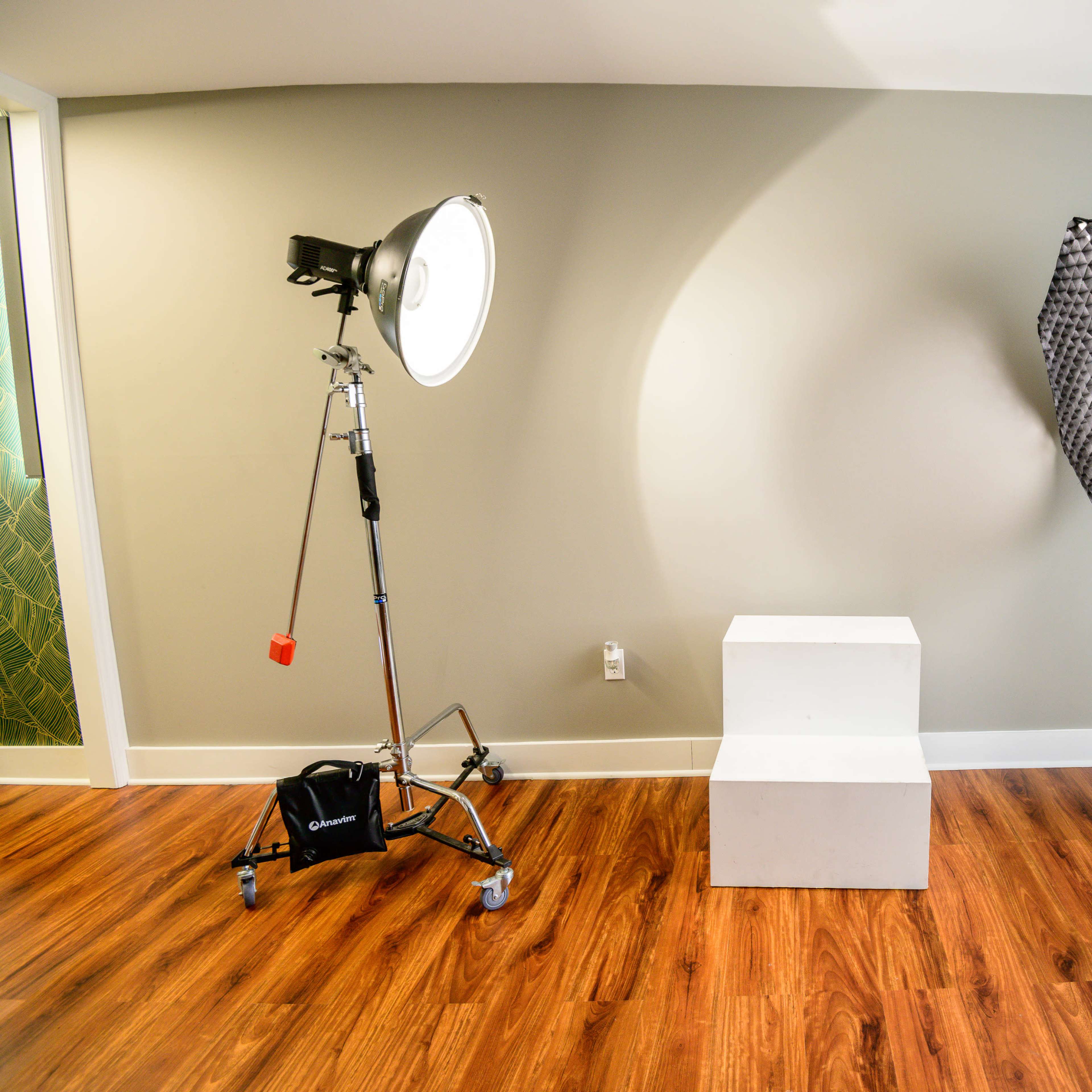A photography studio setup with two light fixtures positioned on either side of a white pedestal on a wooden floor.