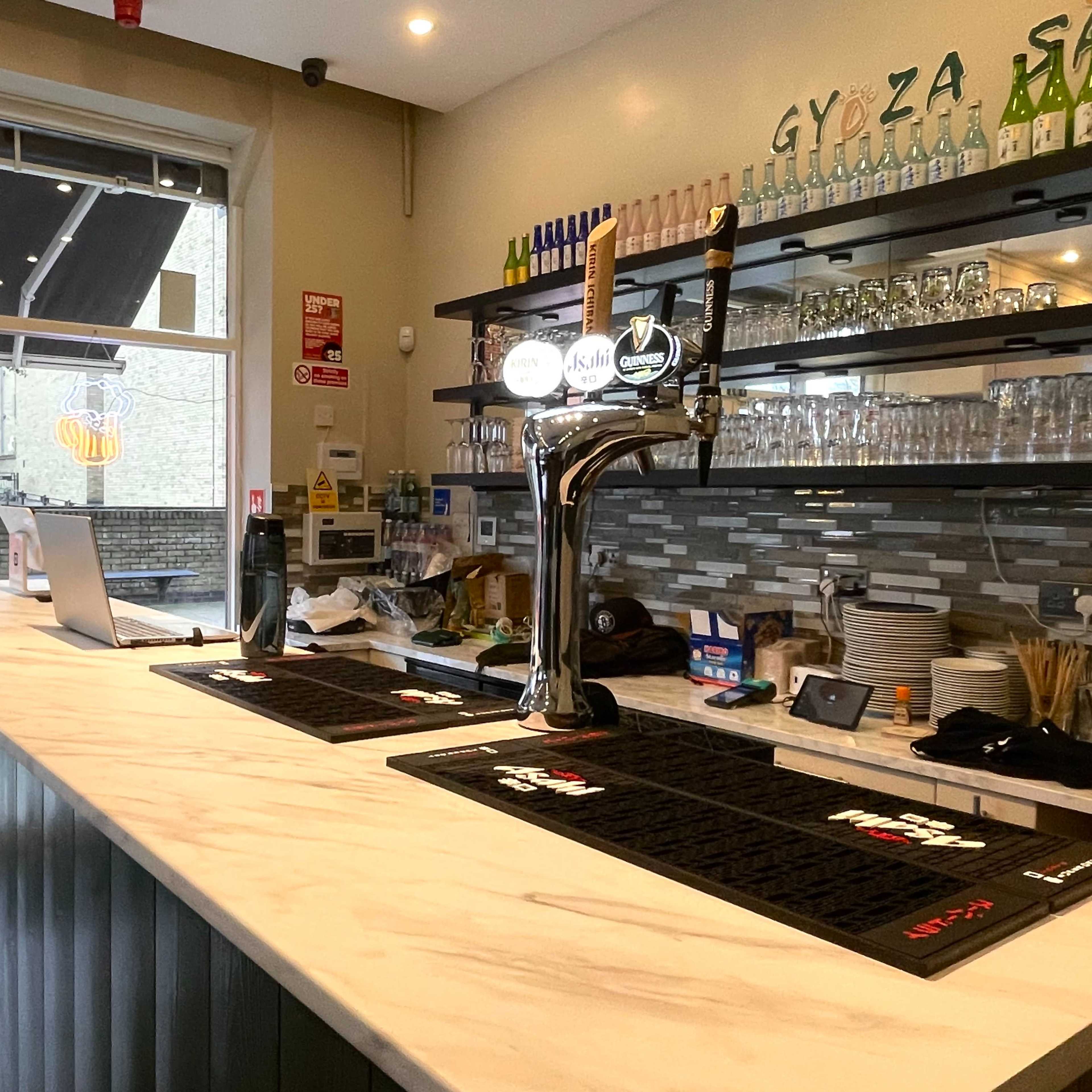 A clean bar area with a marble countertop, a beer tap, and shelves stocked with glassware and bottles.