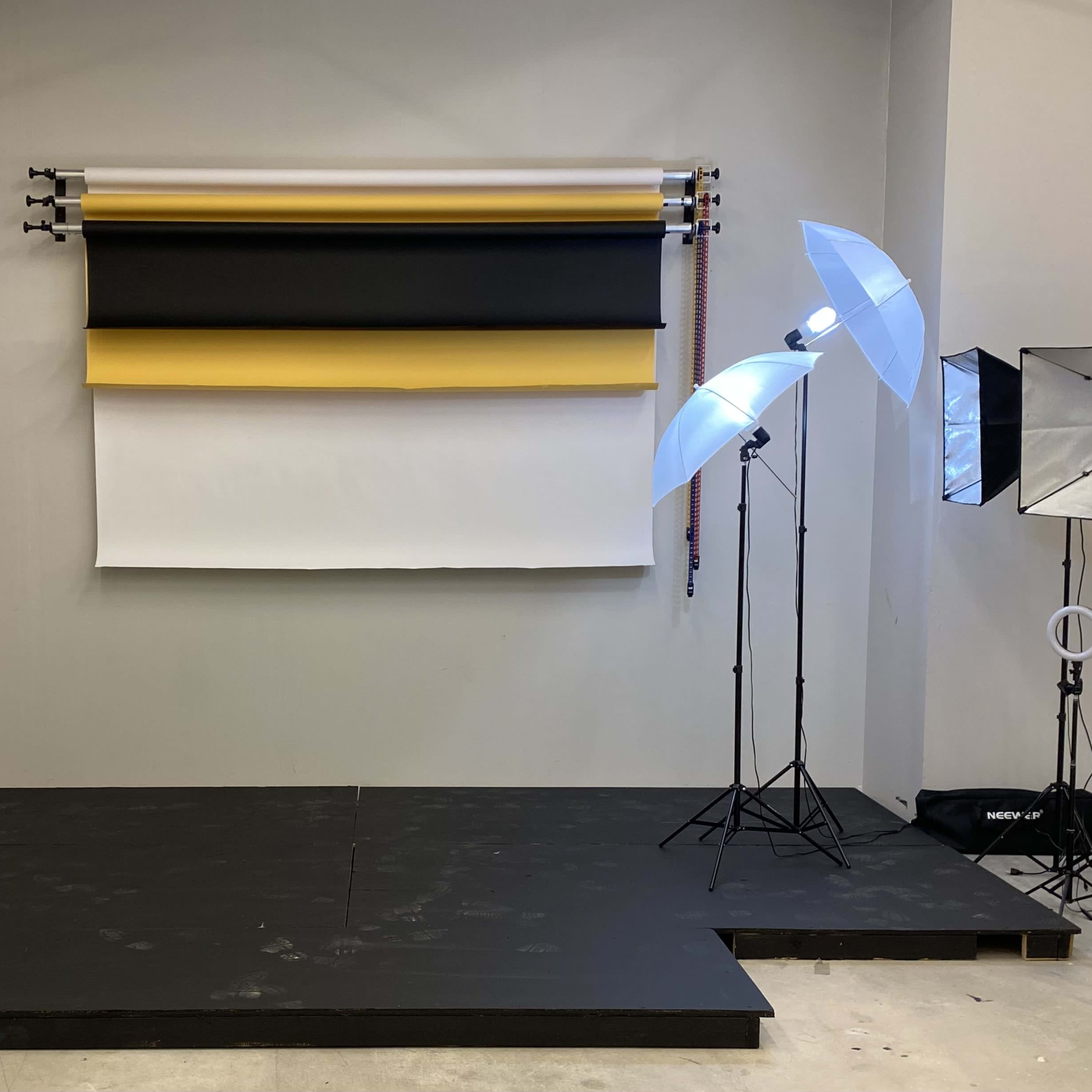 A photography studio setup with a backdrop of colored rolls and several lighting equipment on stands.