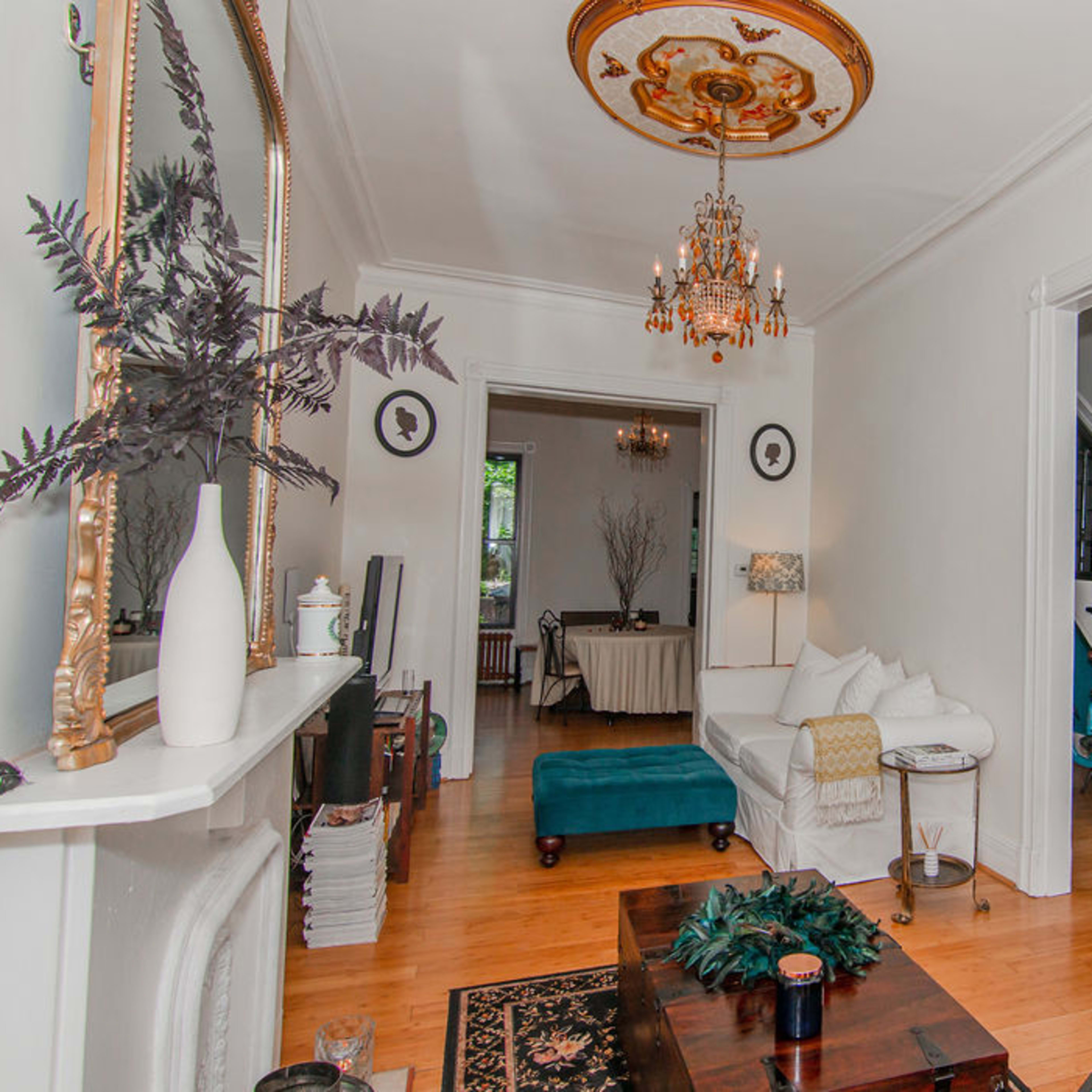 A well-decorated hallway featuring a chandelier, a decorative mirror, and a staircase, with a seating area that includes a sofa and a coffee table.