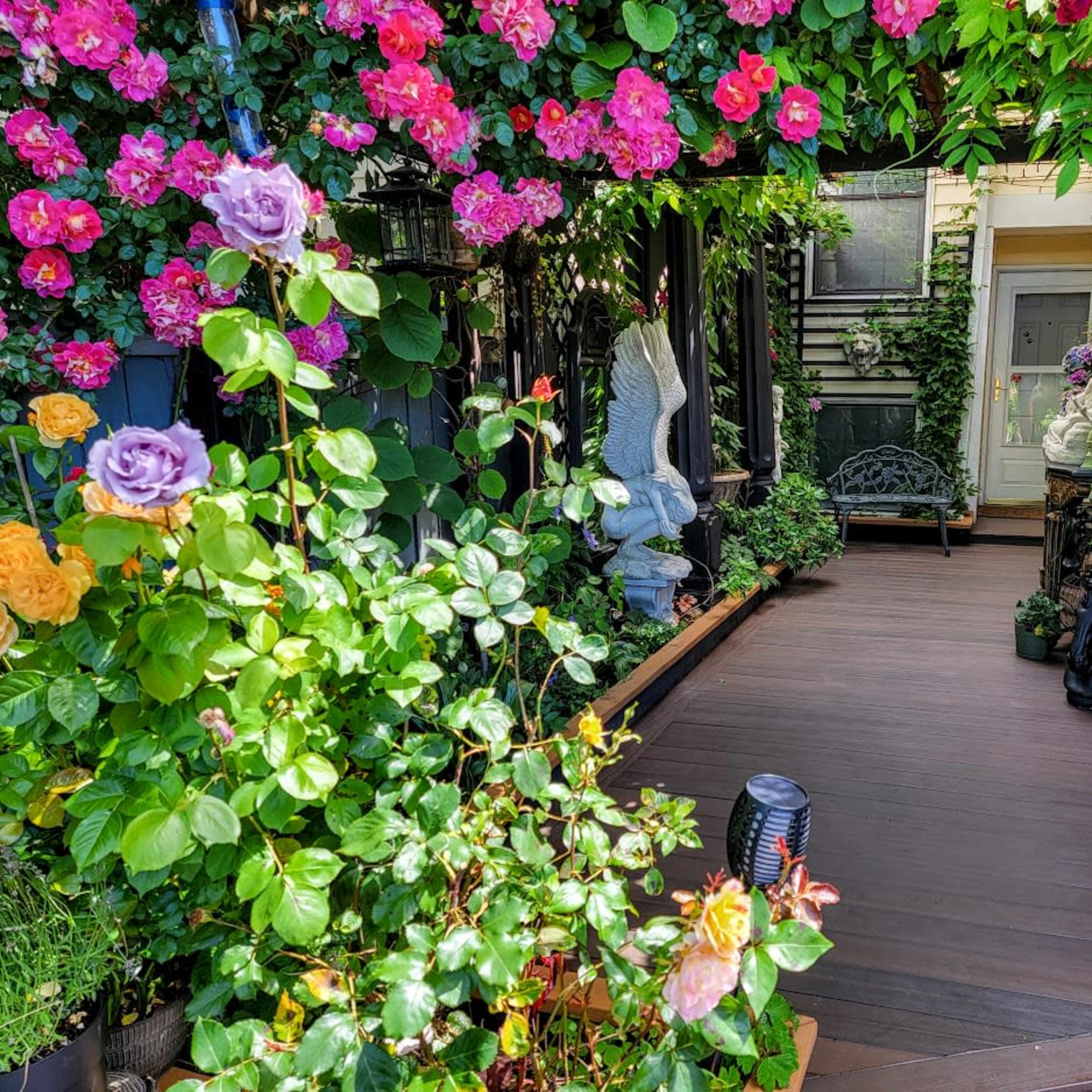 A pathway adorned with vibrant flowers and greenery leads to a doorway framed by decorative elements.