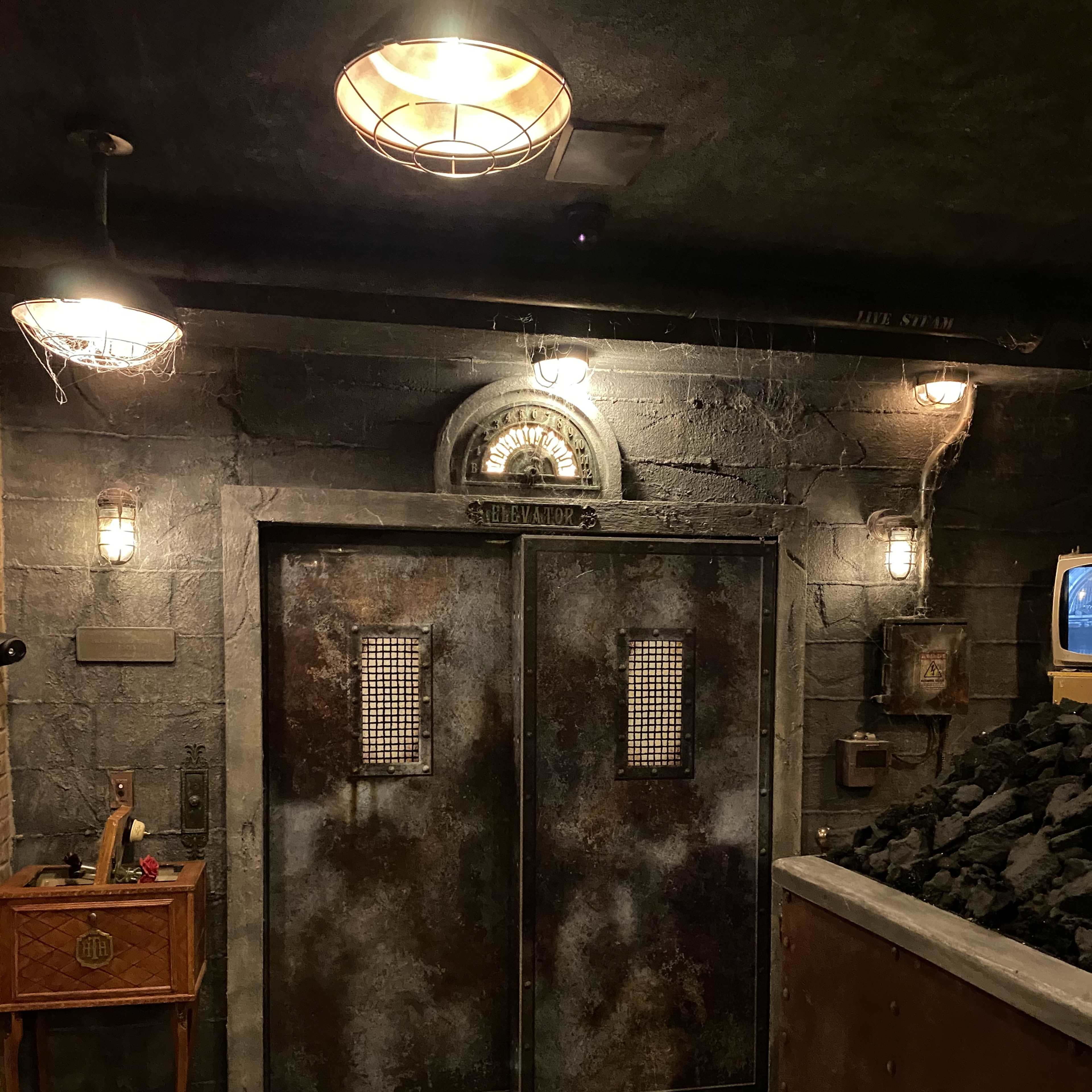 A dimly lit, industrial-styled space featuring a pair of large, aged metal doors with a grated design.