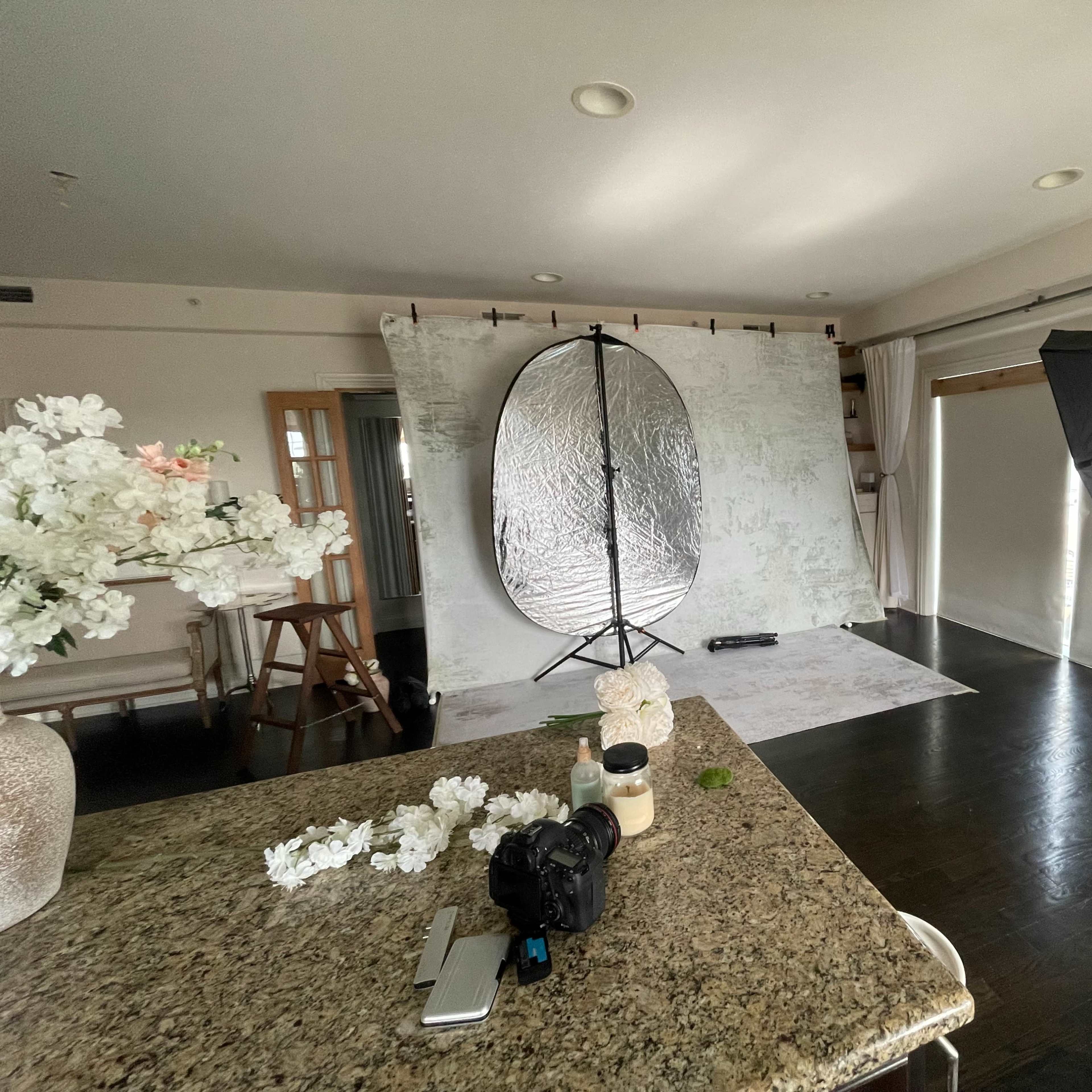 A photography studio setup with a reflector, a backdrop, and studio lights arranged in a well-lit room.