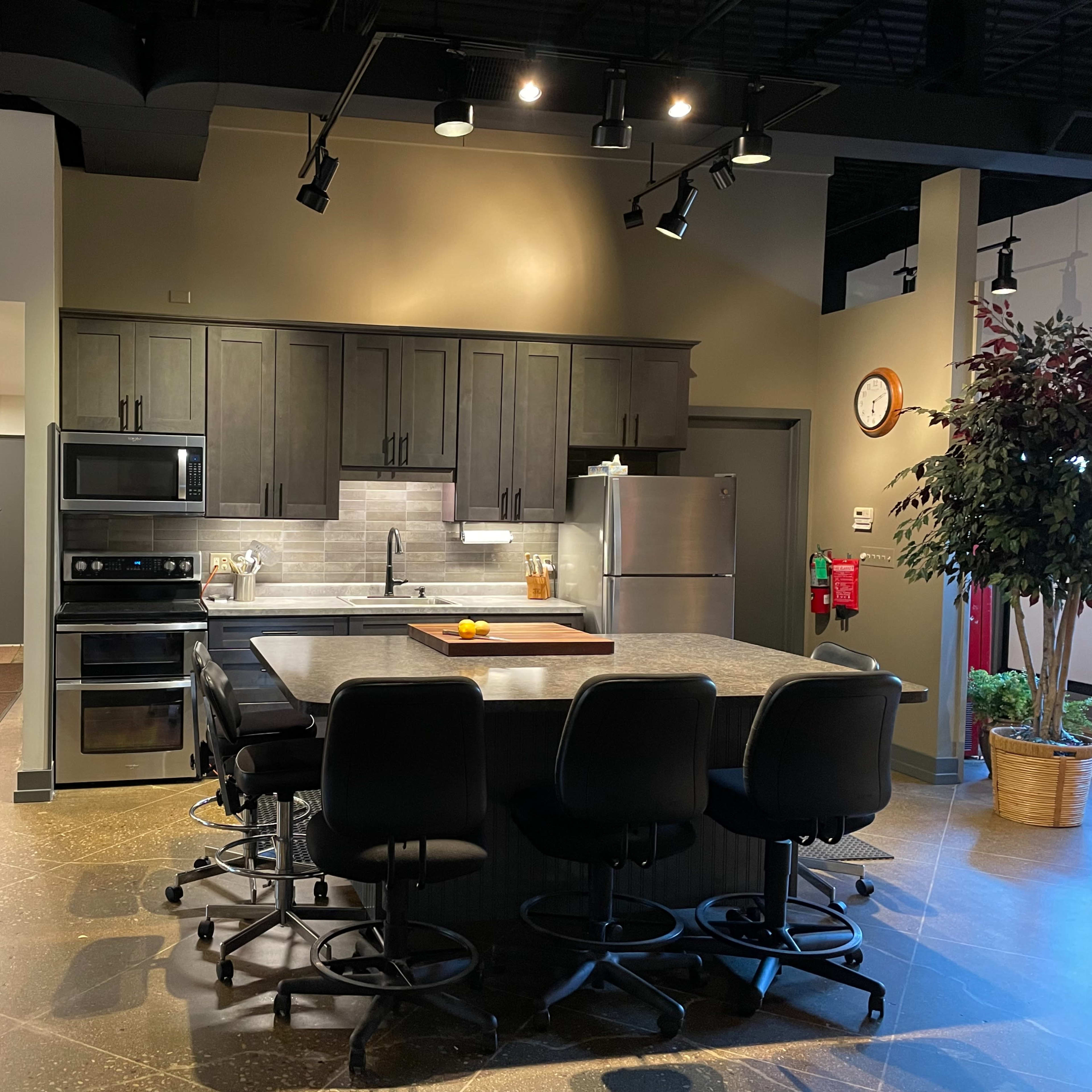A modern kitchen with dark cabinetry, stainless steel appliances, and a large island with bar stools.