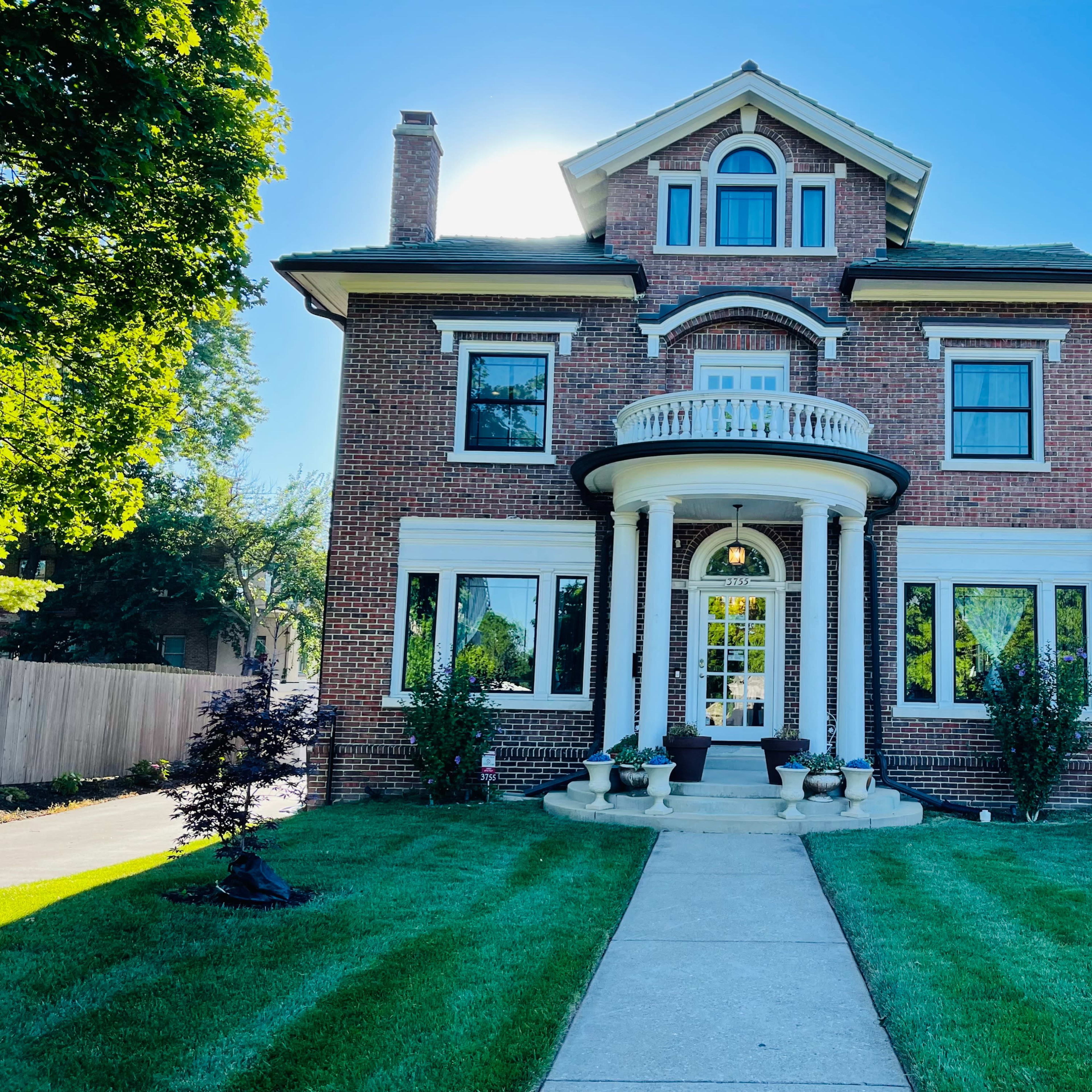 A large brick house with a prominent front porch and well-maintained landscaping.