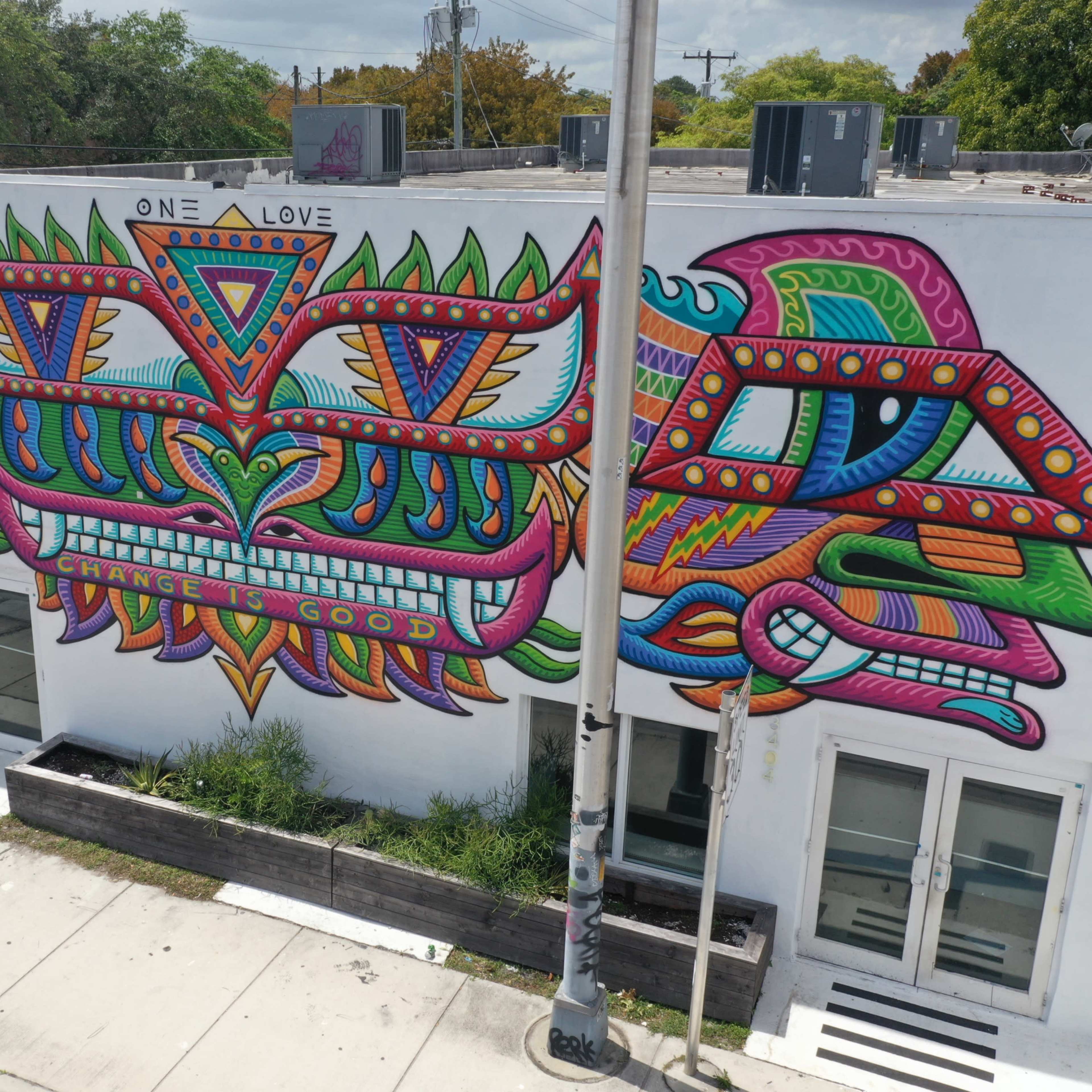 A colorful mural on the side of a building featuring abstract designs and the phrase "One Love" prominently displayed in the center.