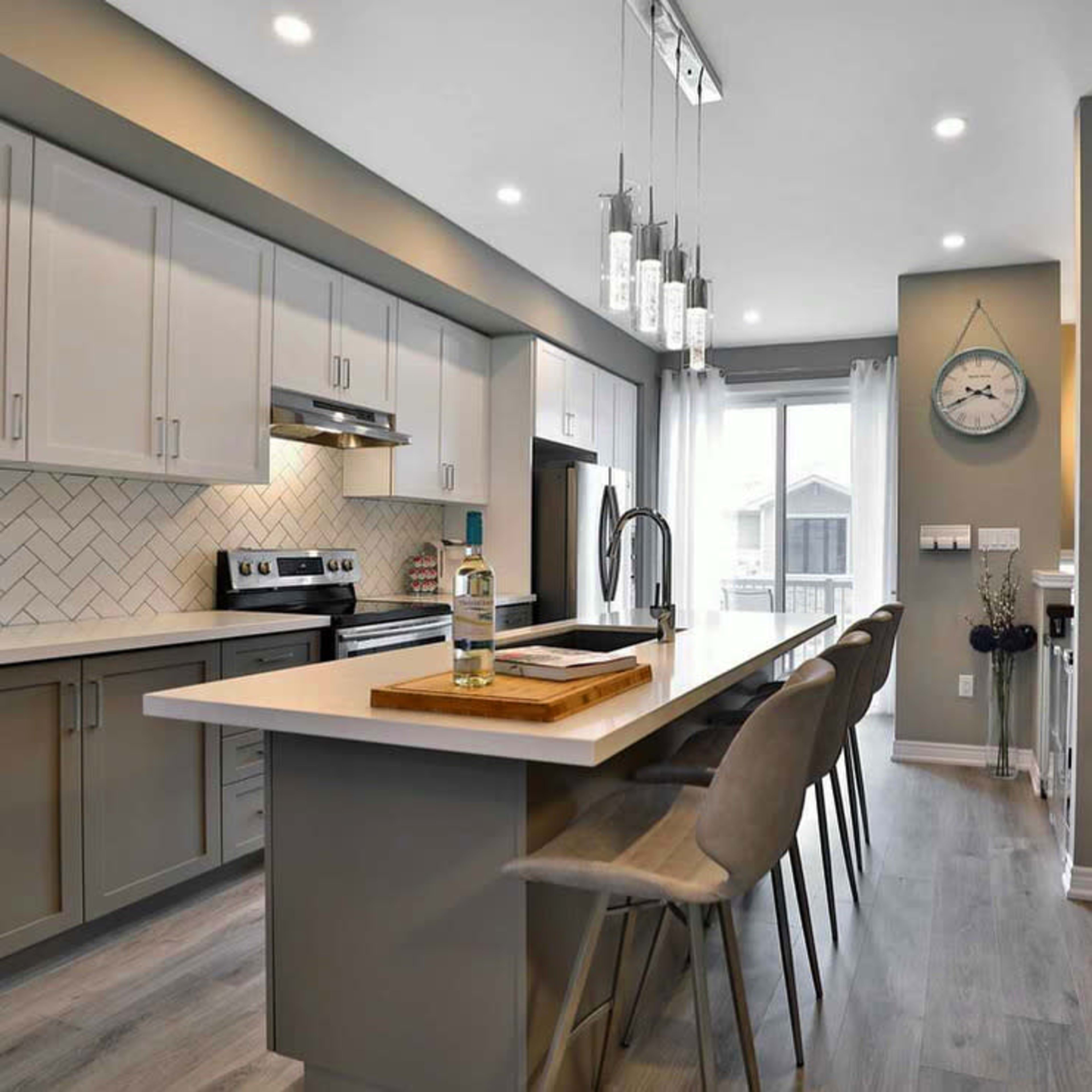 A modern kitchen featuring light gray cabinetry, a center island with bar seating, and a large window that allows natural light to enter the space.