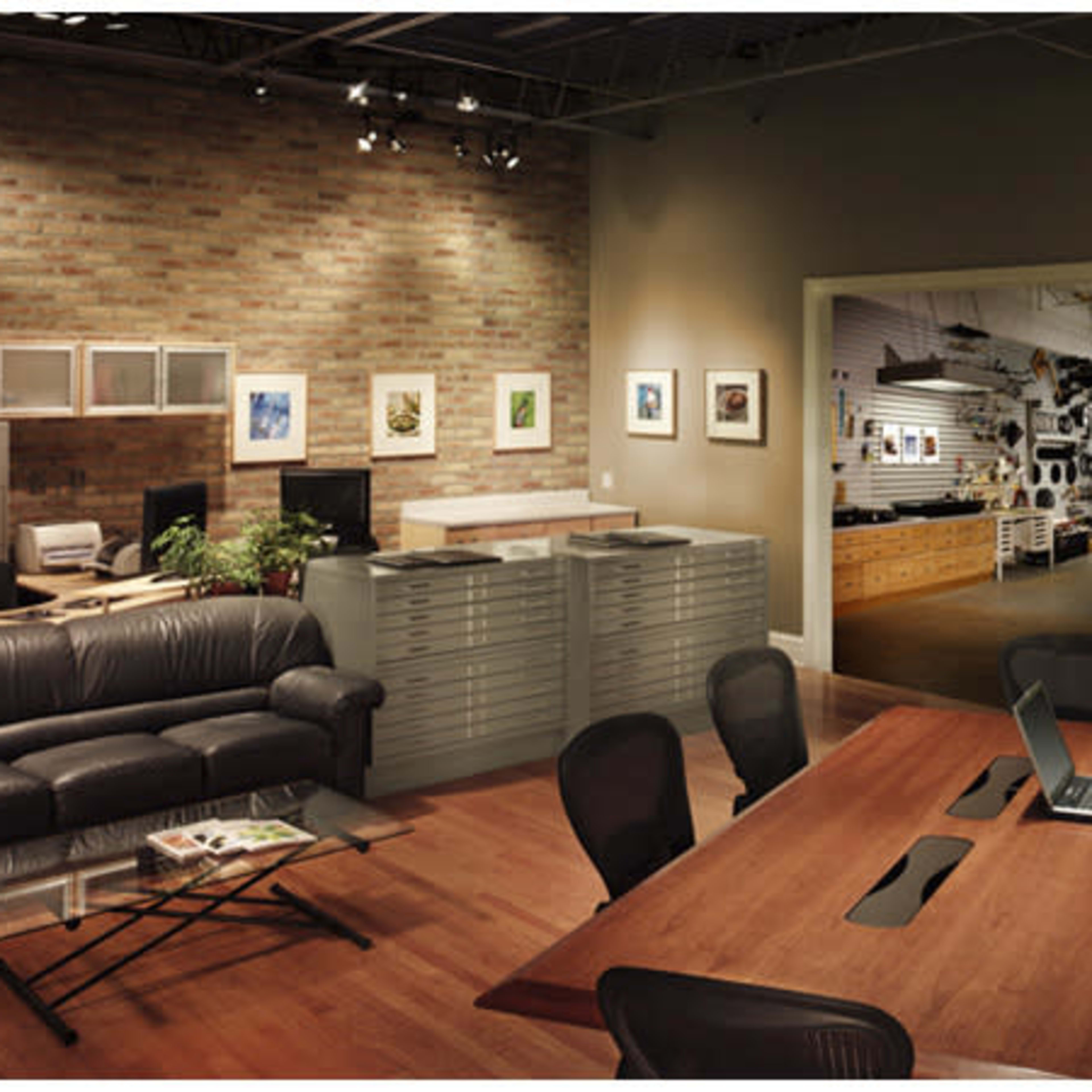 A modern office space featuring a conference table, black chairs, a leather sofa, cabinets, and art on the walls.