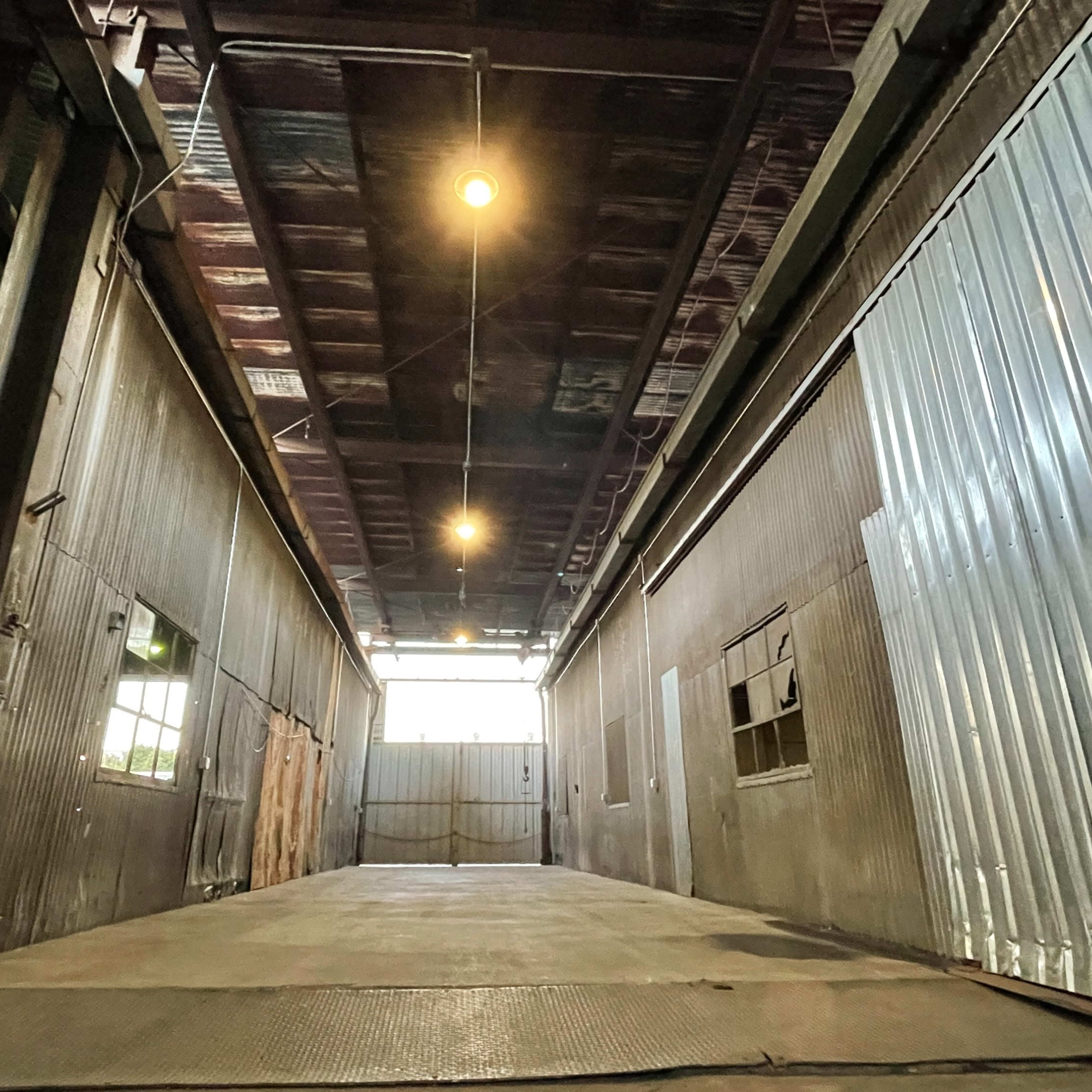 A long, industrial hallway with metal walls and overhead lights illuminating the space.
