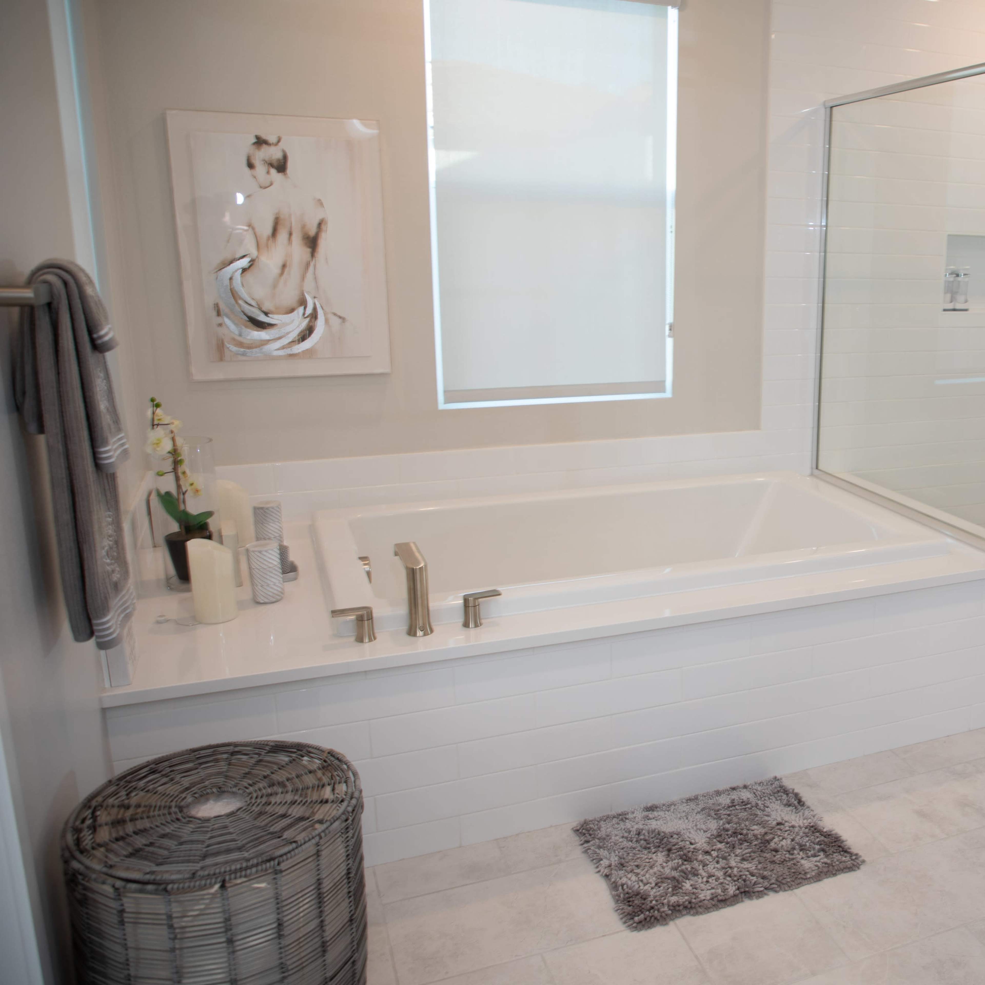 A modern bathroom featuring a glass shower, a freestanding tub, a wall-mounted mirror, and light-colored tiles.