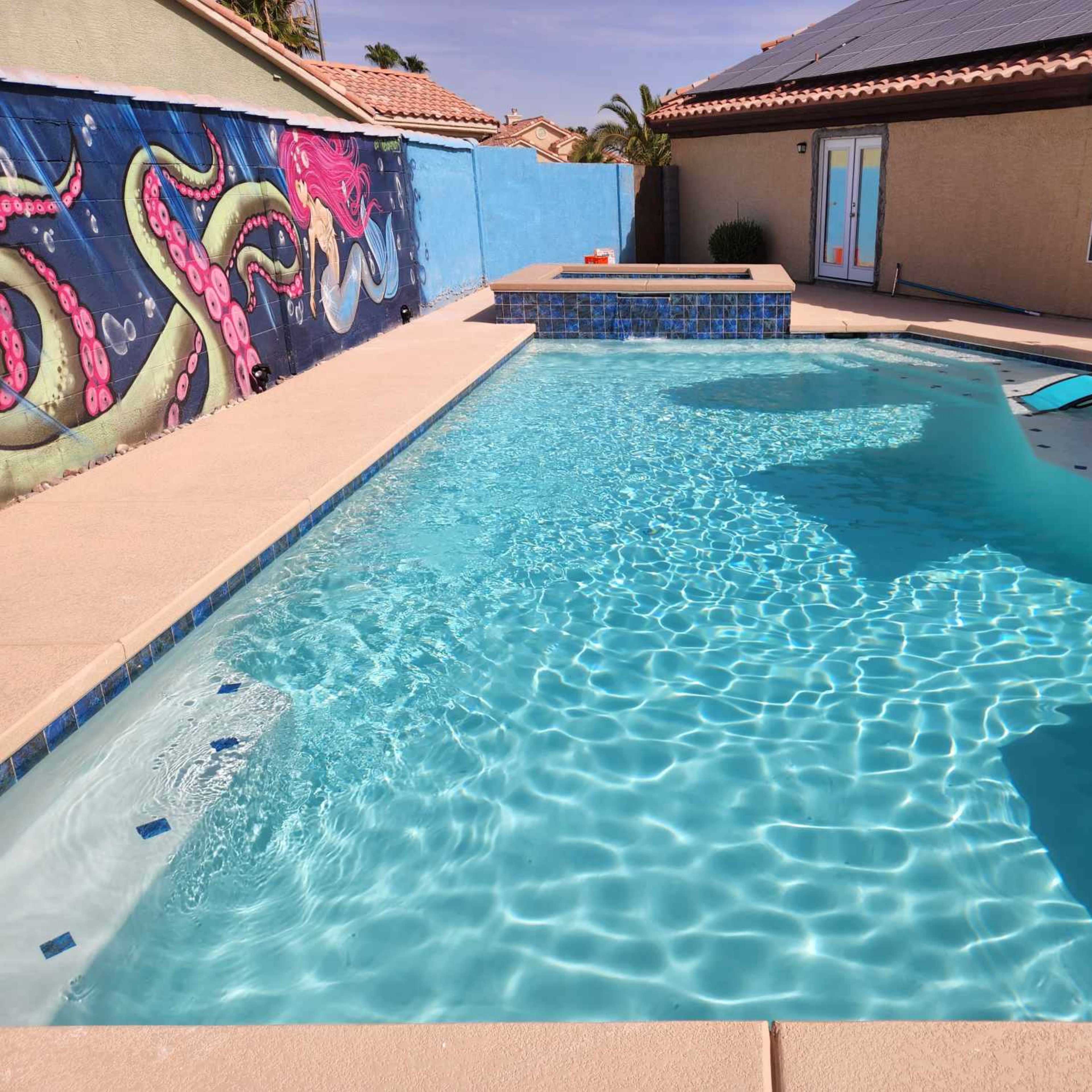 The scene shows a clear swimming pool surrounded by a patio, with a colorful wall mural of an octopus visible in the background.