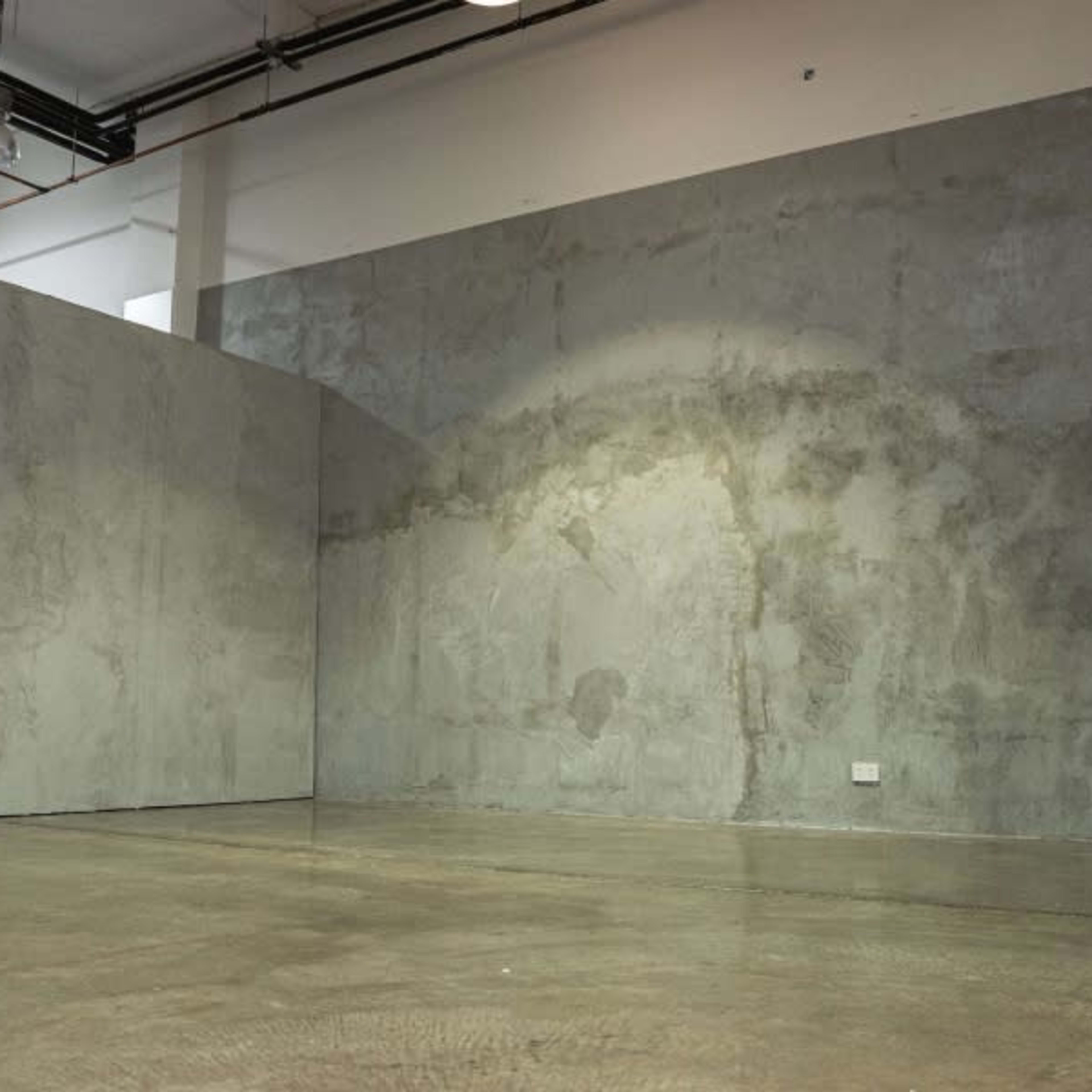 An empty interior space with two large concrete walls and a polished concrete floor.