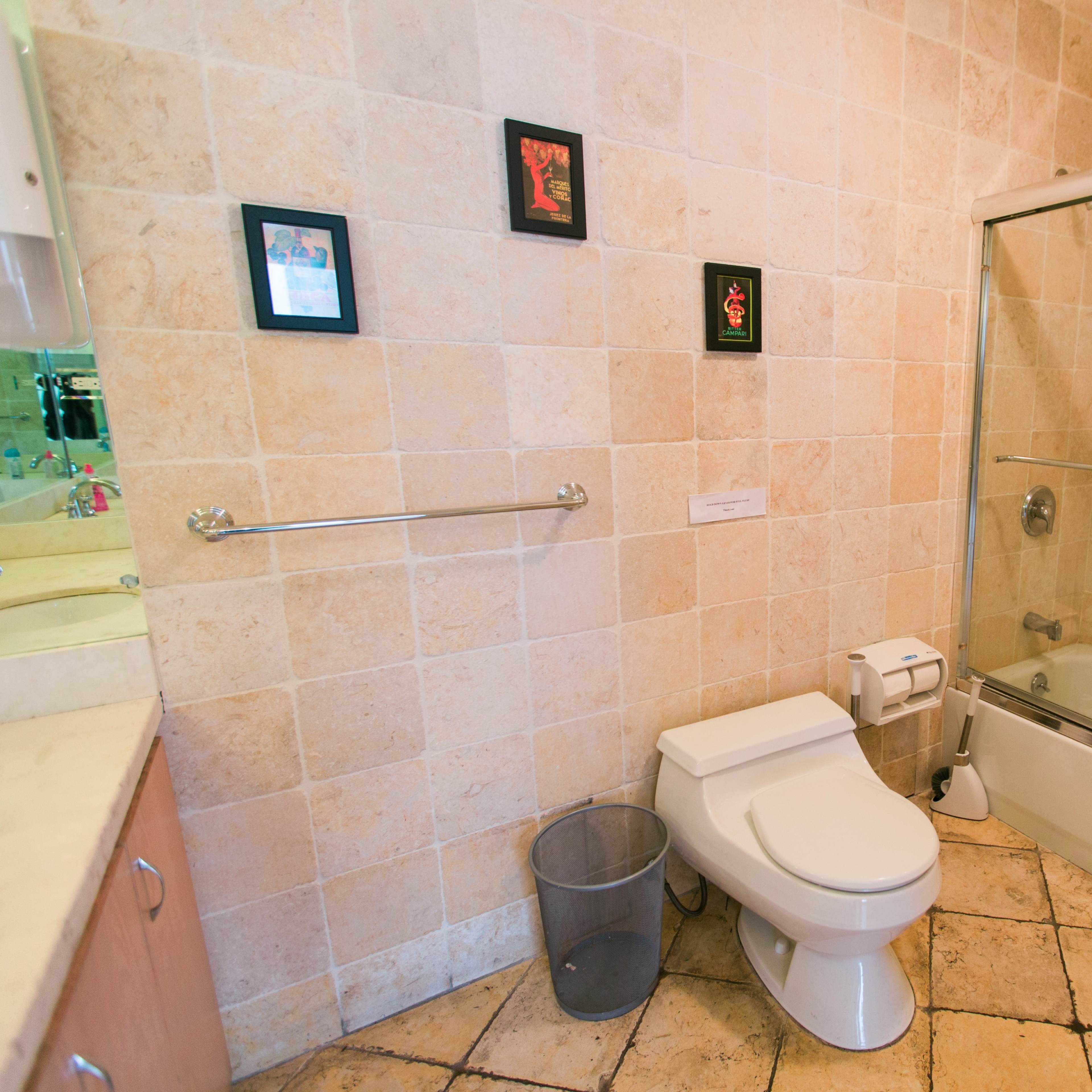 A bathroom featuring a shower-tub combination, a toilet, and wall-mounted artwork.