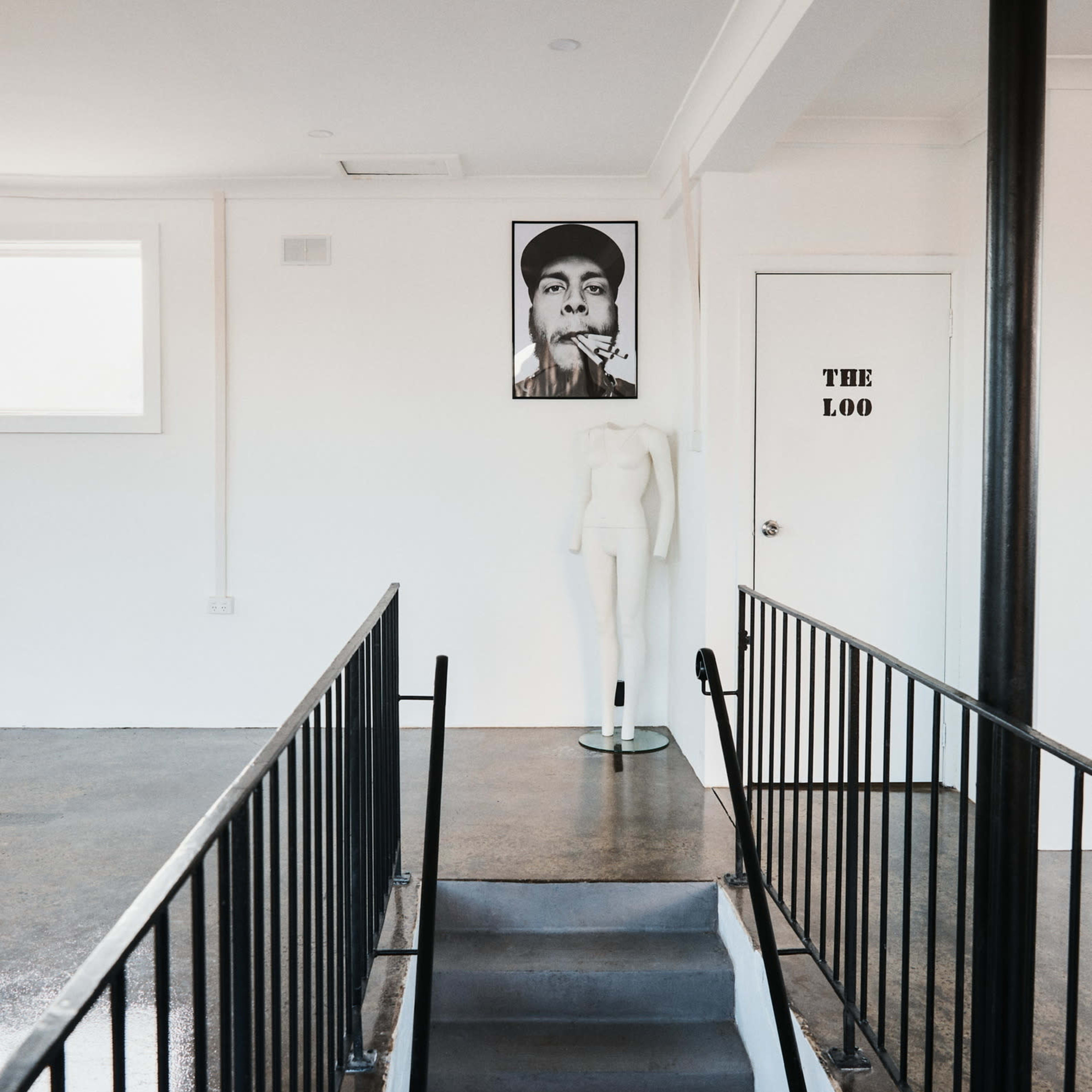 A staircase leading to a room with a large portrait on the wall and a mannequin positioned nearby, with a door labeled "THE LOO" visible.