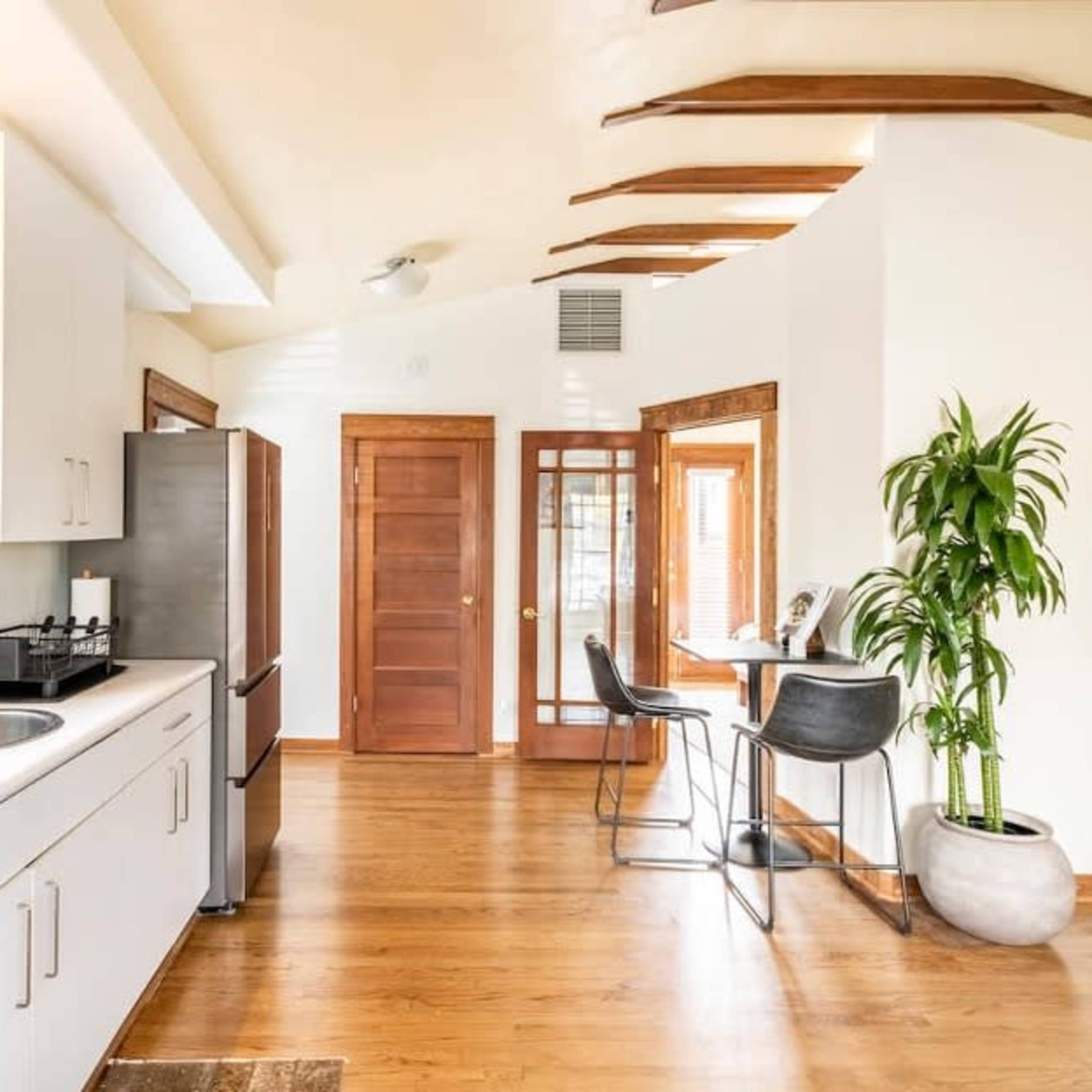 A modern kitchen and dining area with a double sink, stainless steel appliances, and a small table with chairs beside a large window.