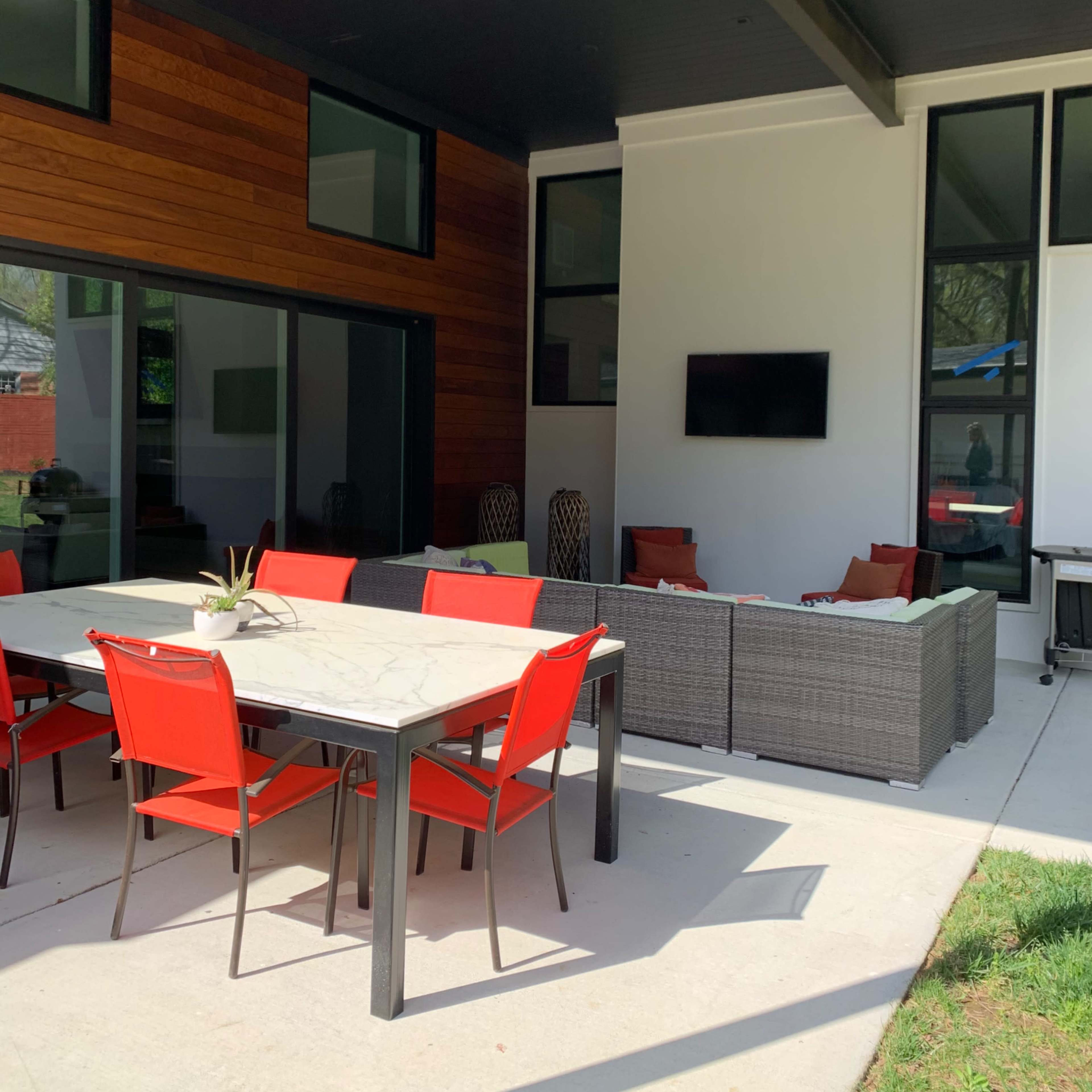 A modern backyard with a swimming pool, lounge chairs, and a nearby changing area.