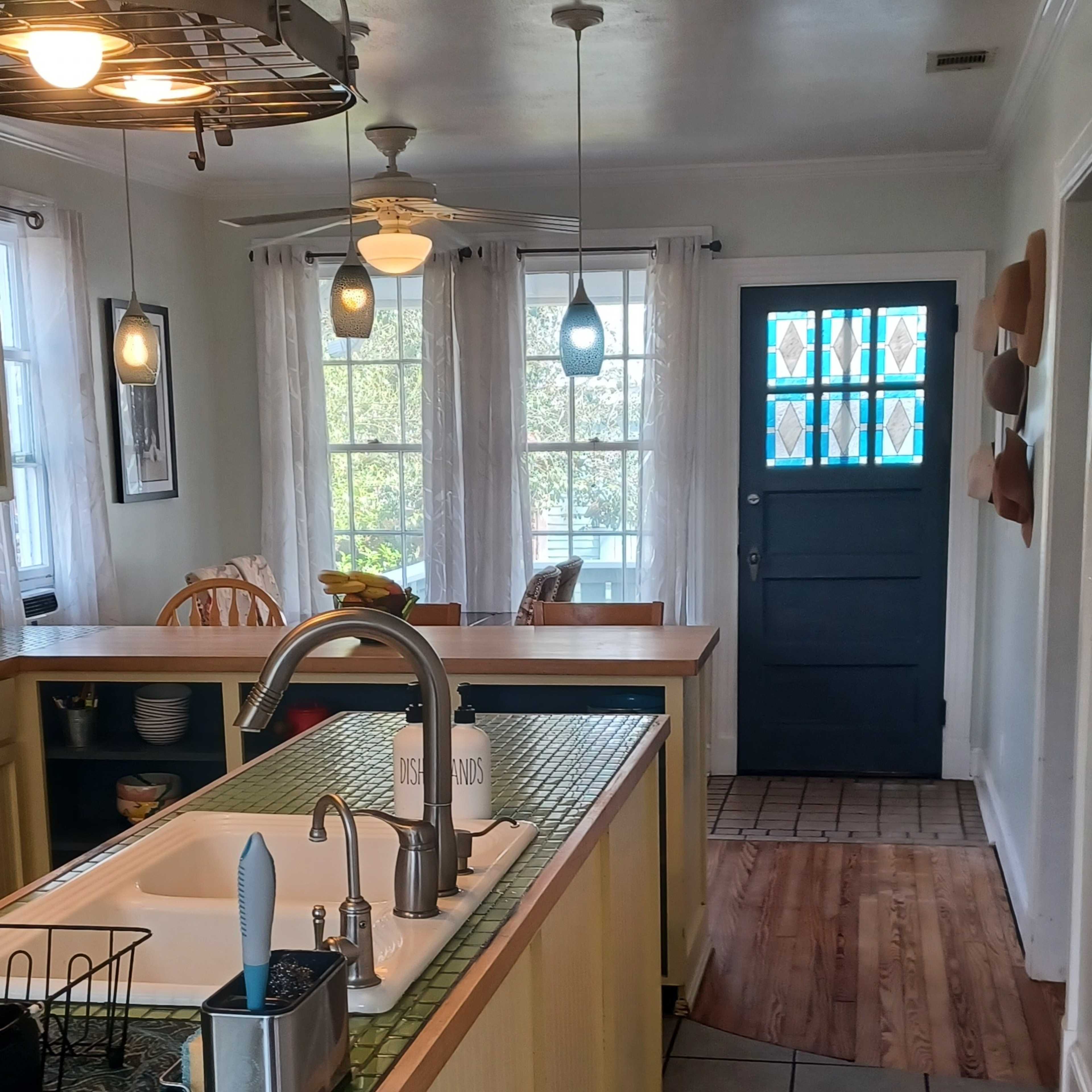 A kitchen area with a central island, a sink, and a doorway leading to a dining area and an entrance.
