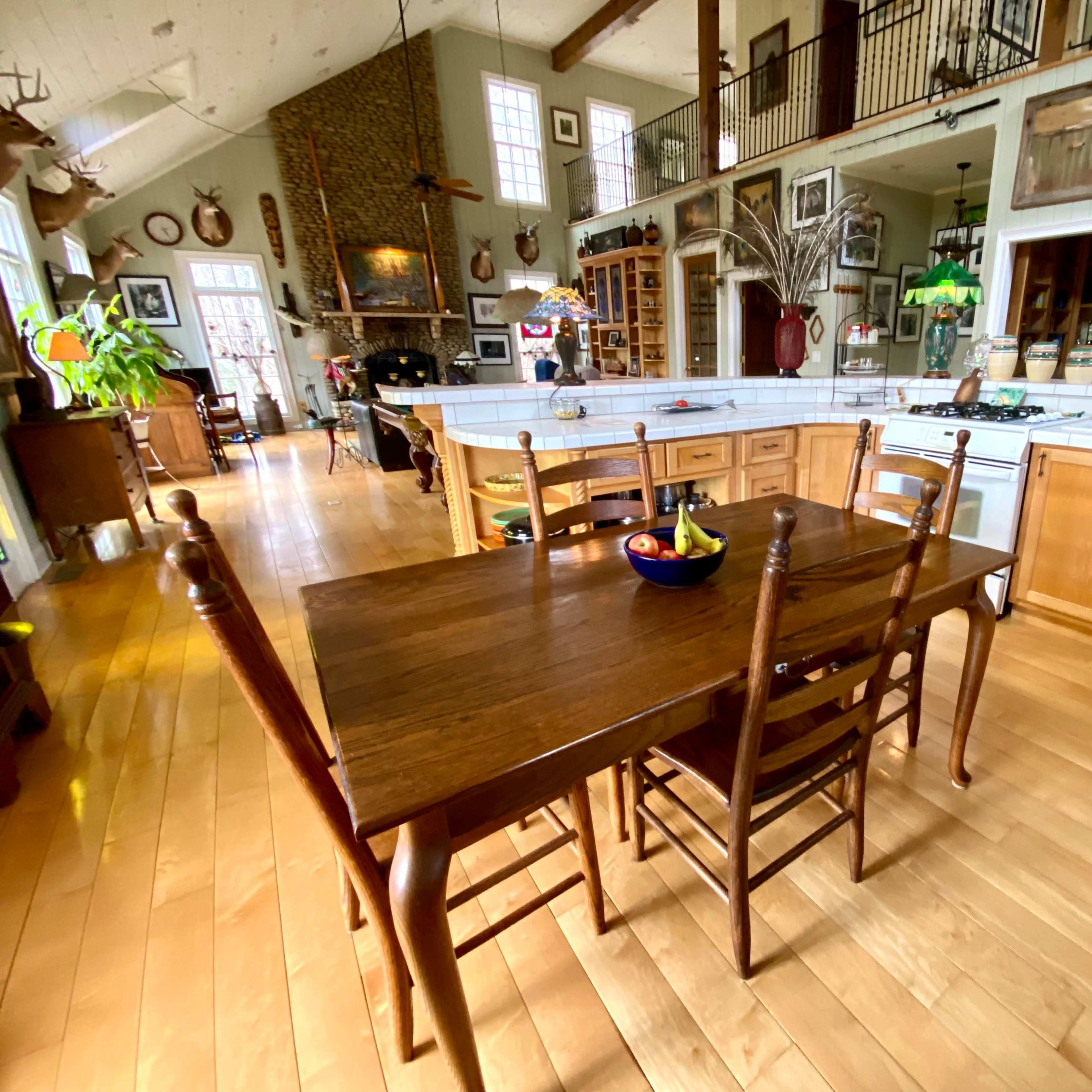 A spacious open-concept kitchen and dining area with a wooden table and chairs set in the foreground, surrounded by various decorative elements and appliances.