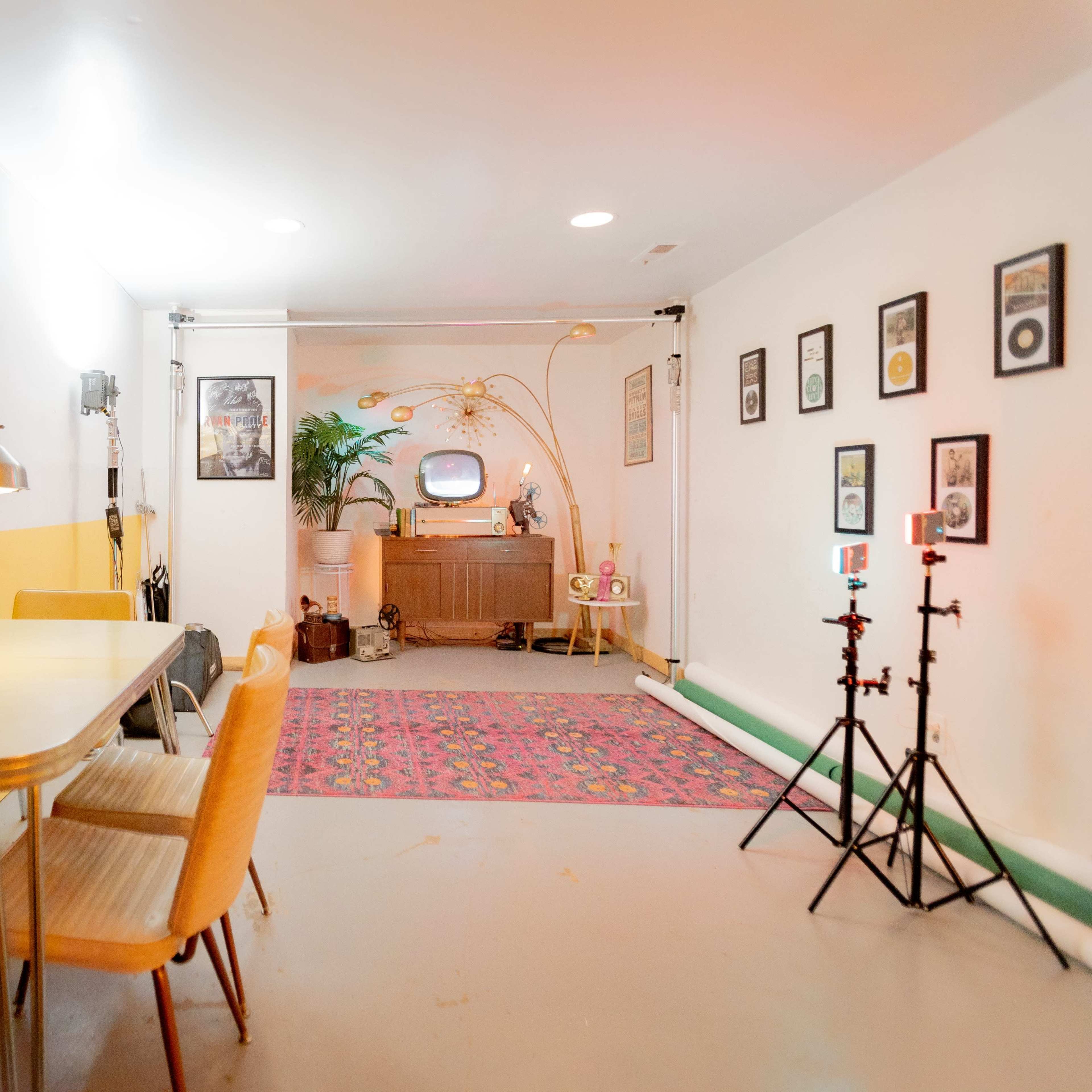A room with a colorful wall, a table and chairs, and a vintage television set, along with framed pictures and decorative items.