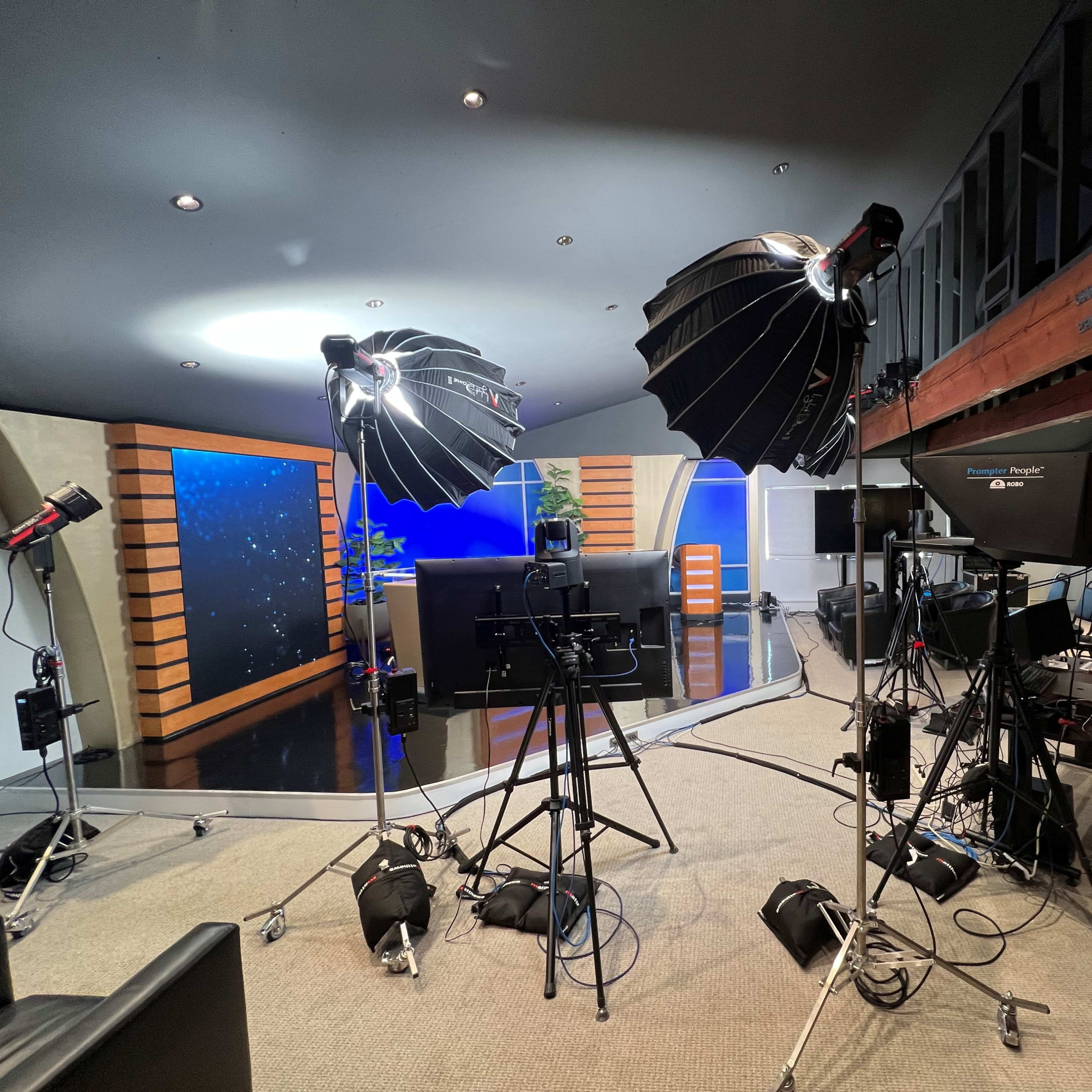 A television studio setup with multiple lighting equipment and a blue backdrop.