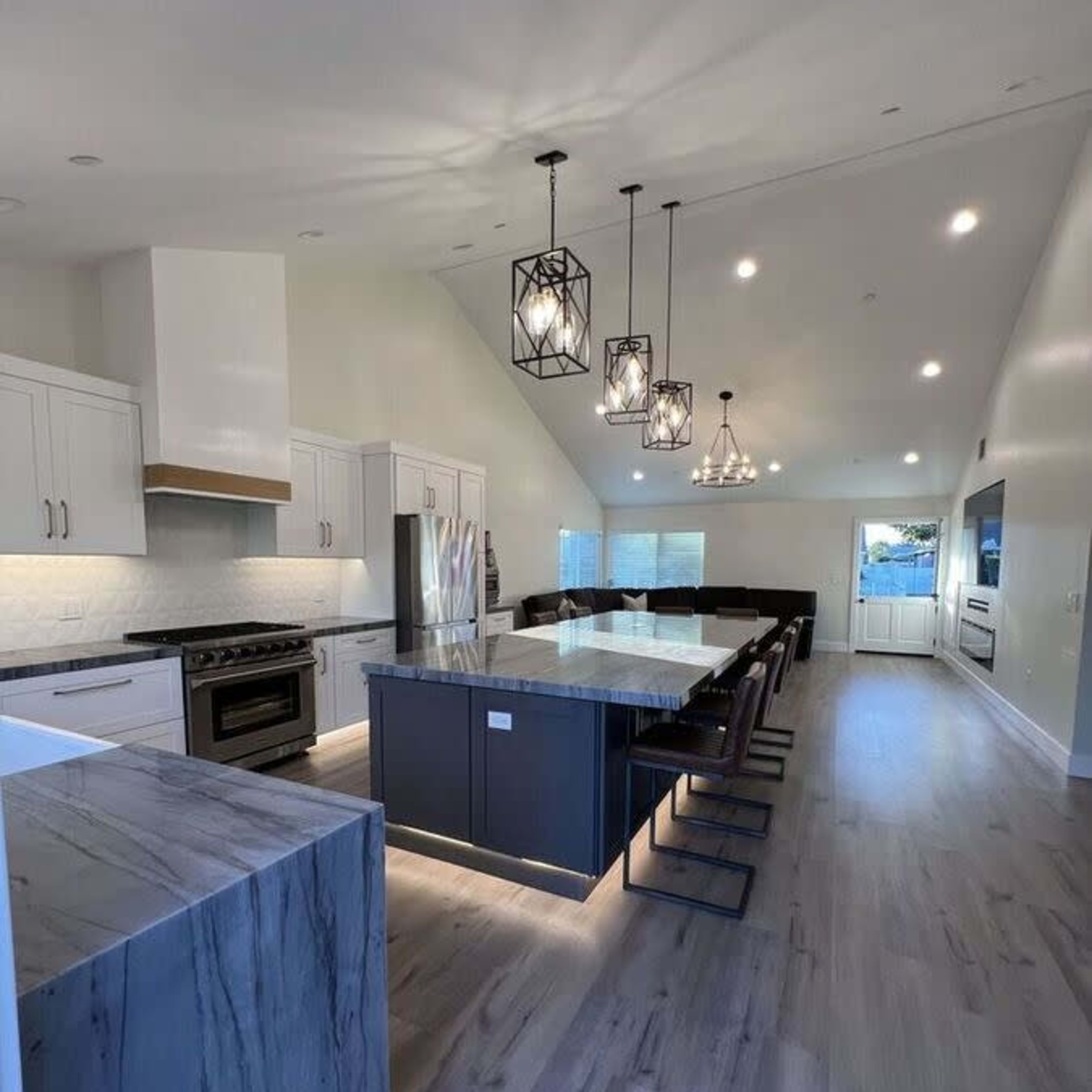 A modern kitchen with a large island, sleek cabinetry, and pendant lighting over a dining area.
