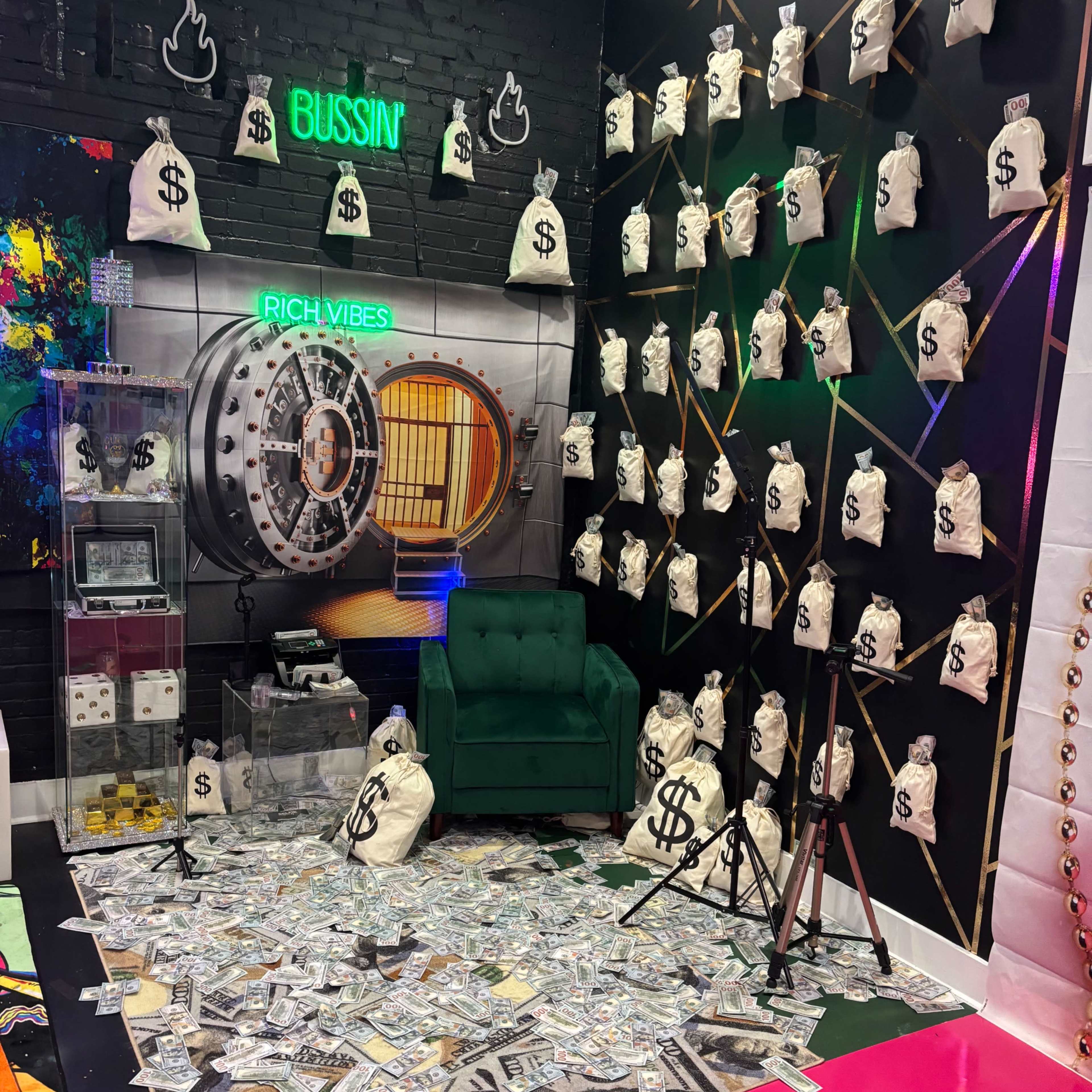 A vibrant room decorated with a green couch, a wall featuring a bank vault, and numerous bags marked with dollar signs scattered across the floor.