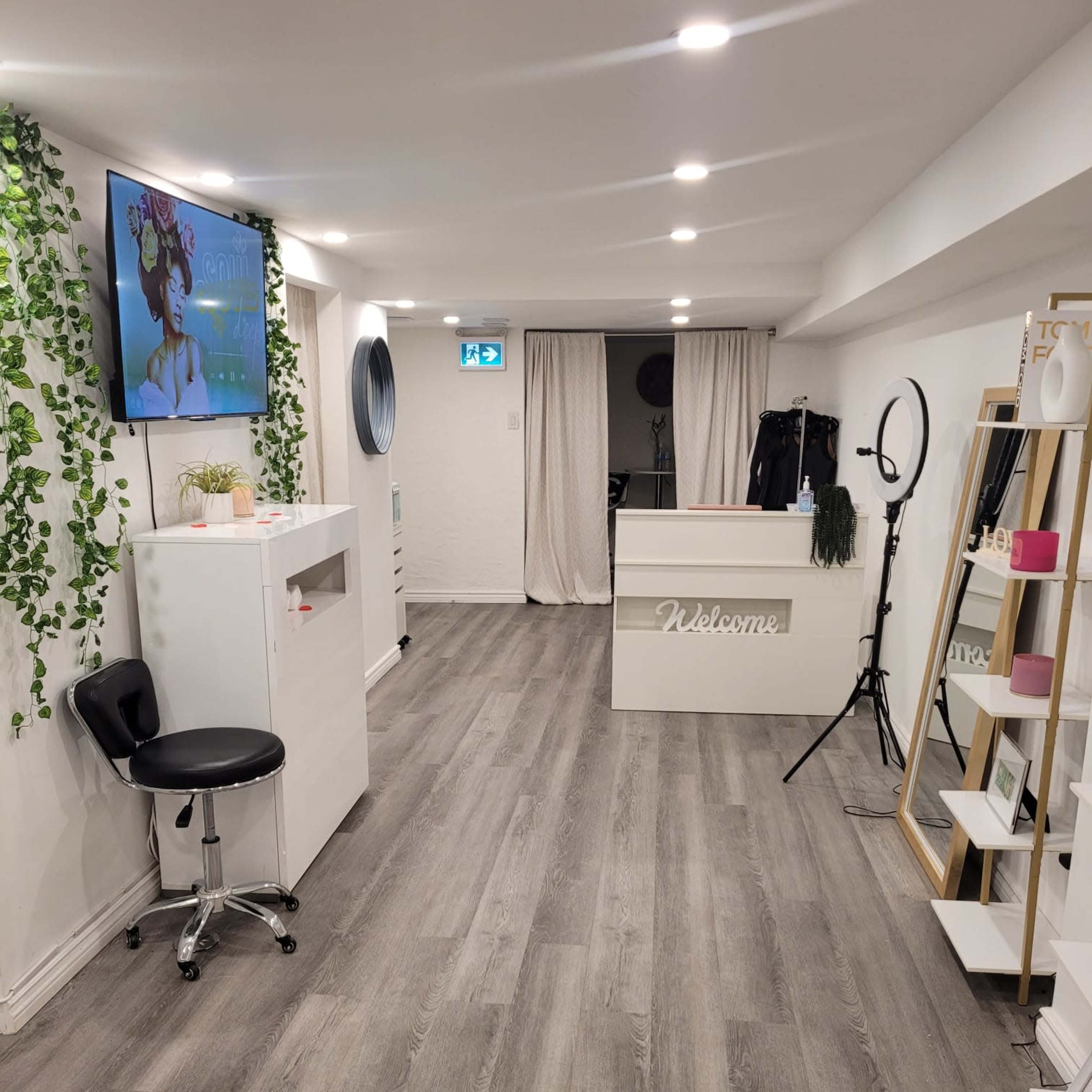 A well-lit interior space resembling a salon or beauty studio, featuring a reception desk, a large mirror, and various display shelves.