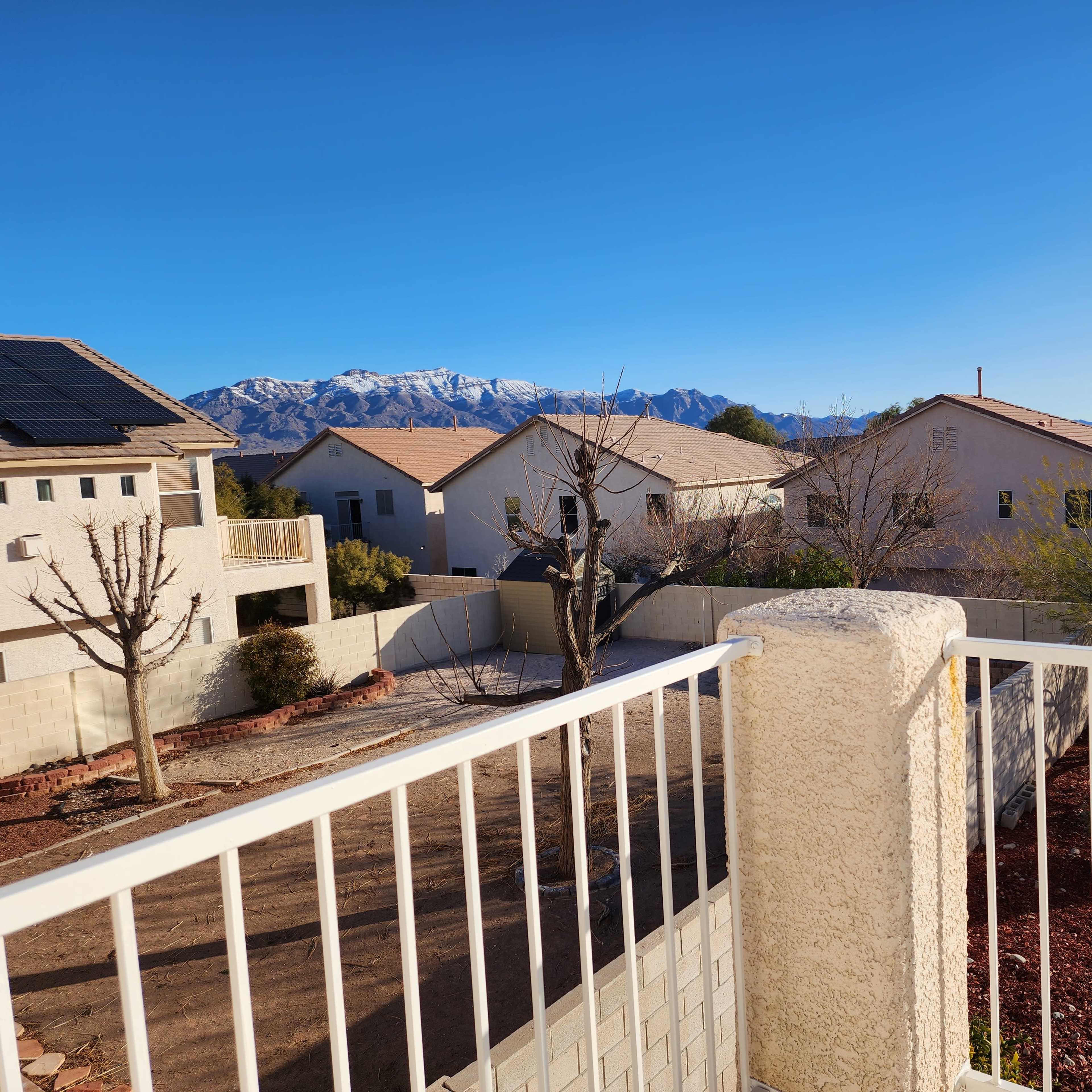 A view from a balcony overlooking neighboring houses with bare trees and mountains in the background.