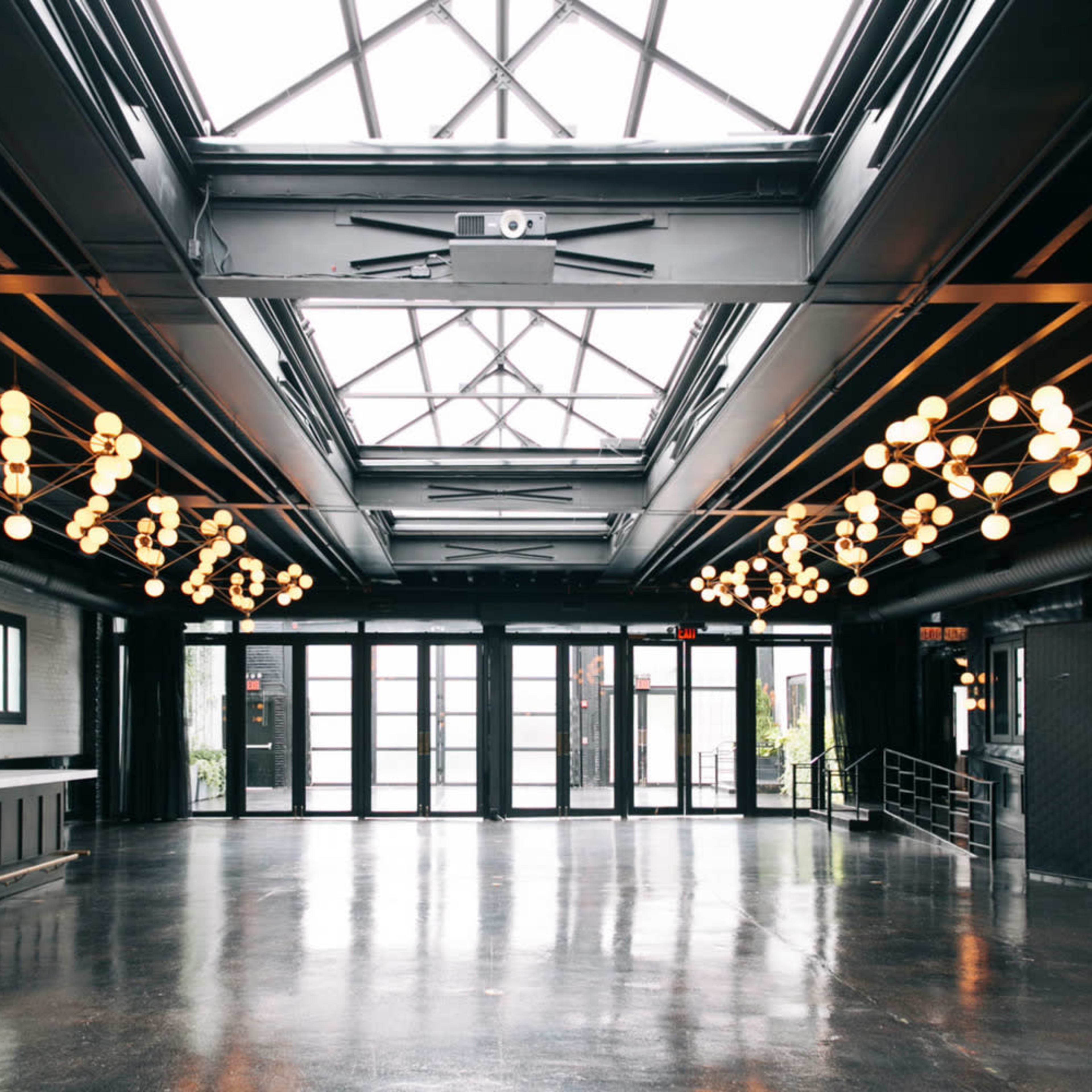 A spacious interior with large windows, black metal beams, and modern lighting fixtures.