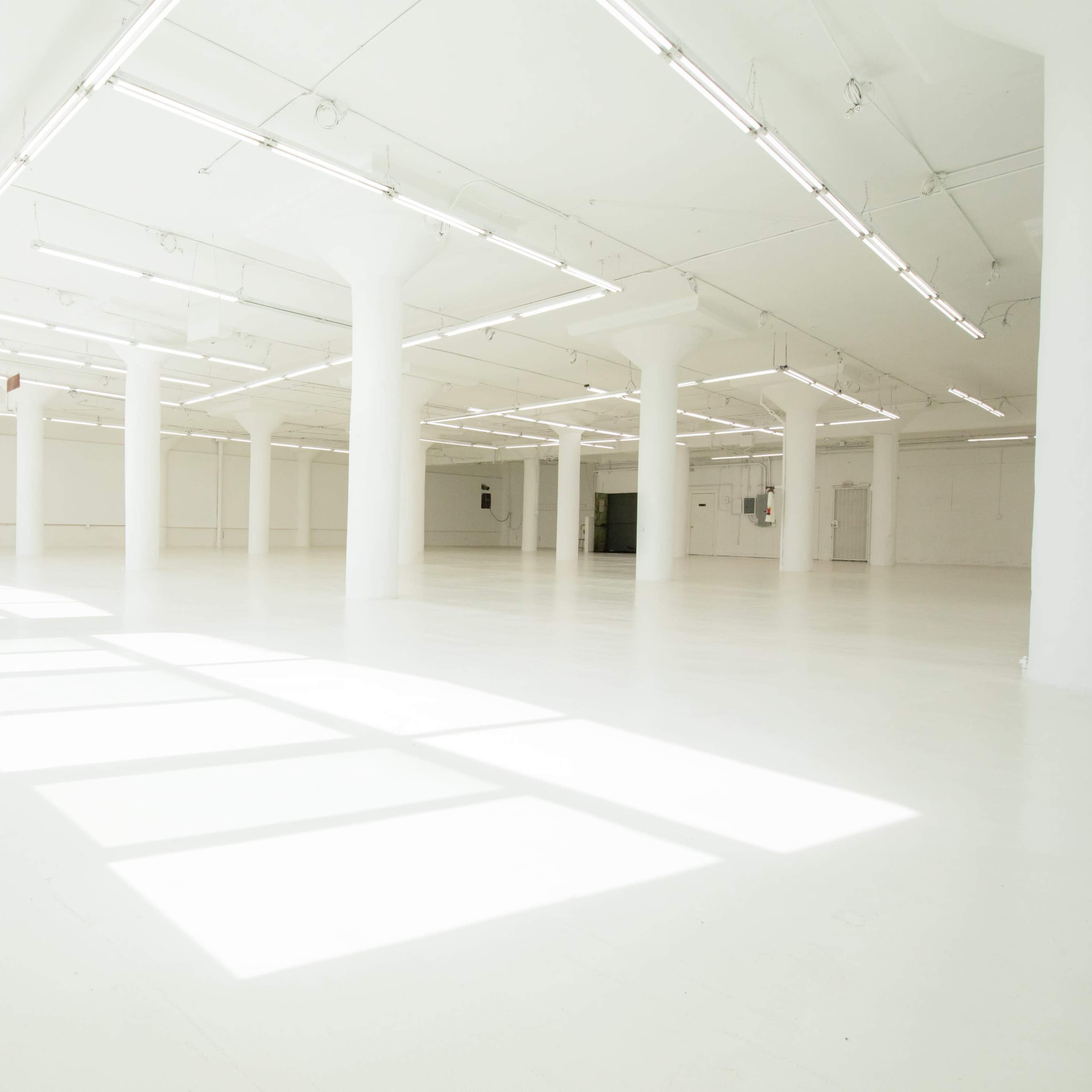 A large, empty, well-lit room with white walls and numerous columns.