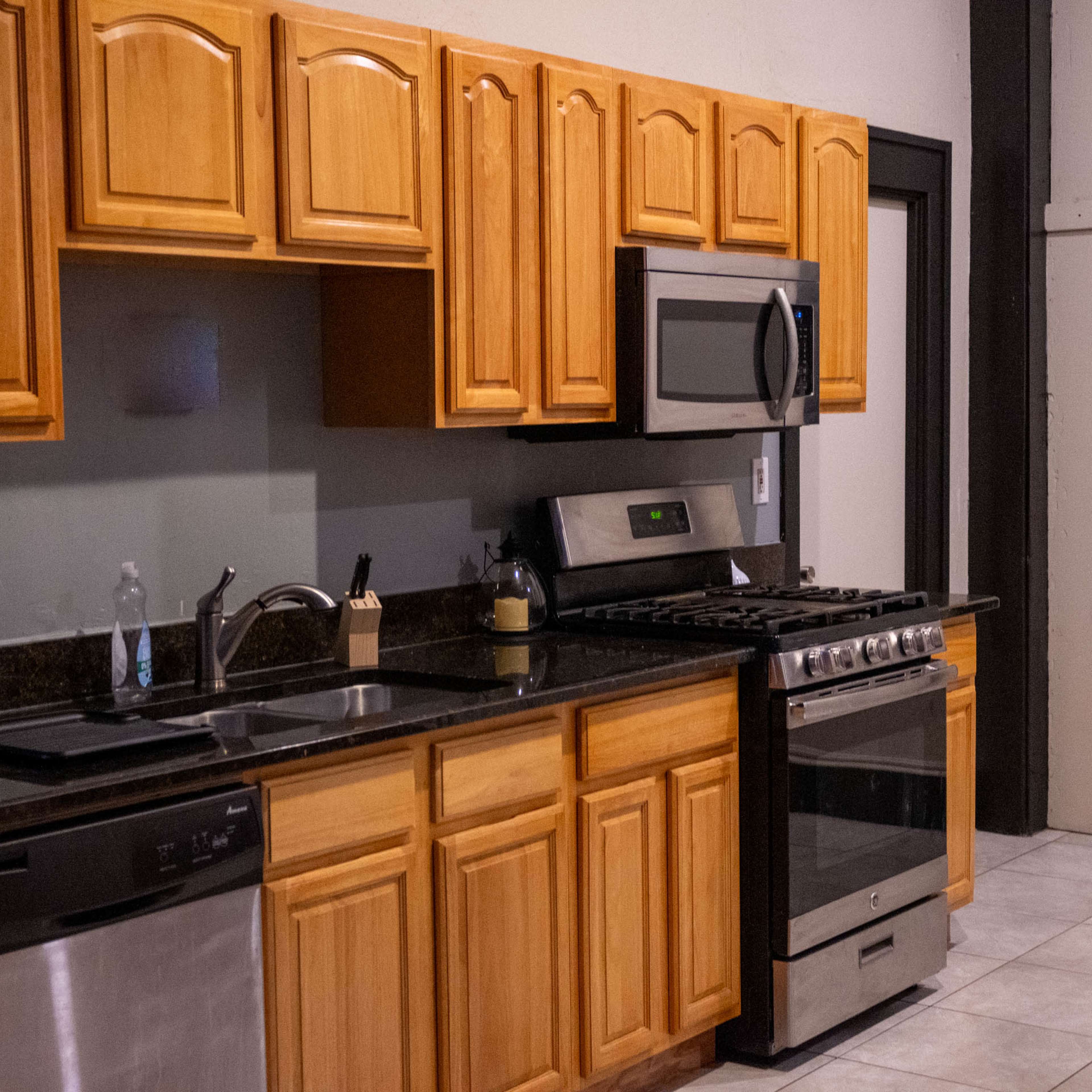 A kitchen with wooden cabinetry, stainless steel appliances, and a granite countertop.