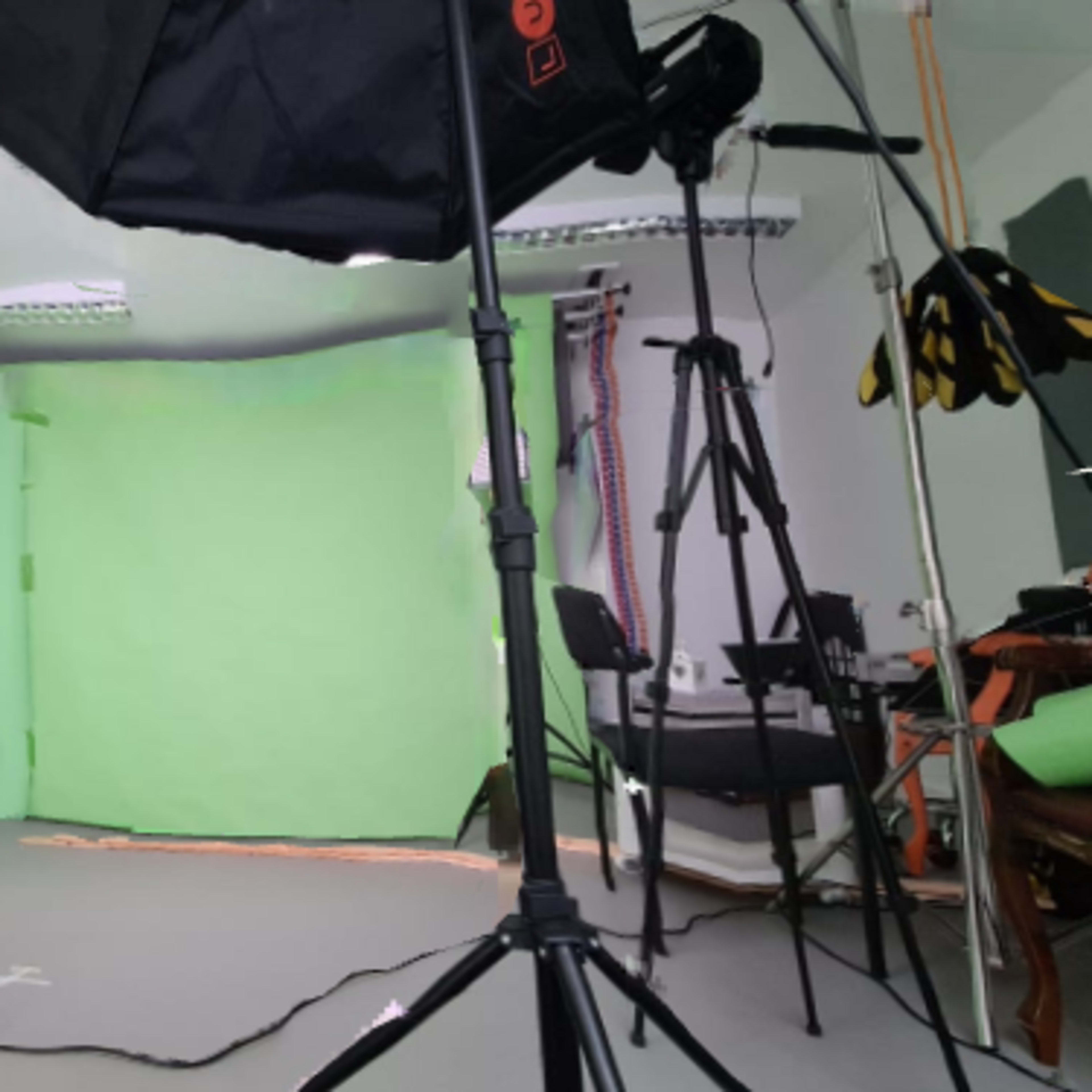 A photography studio set up with green backdrop screens and various light stands.