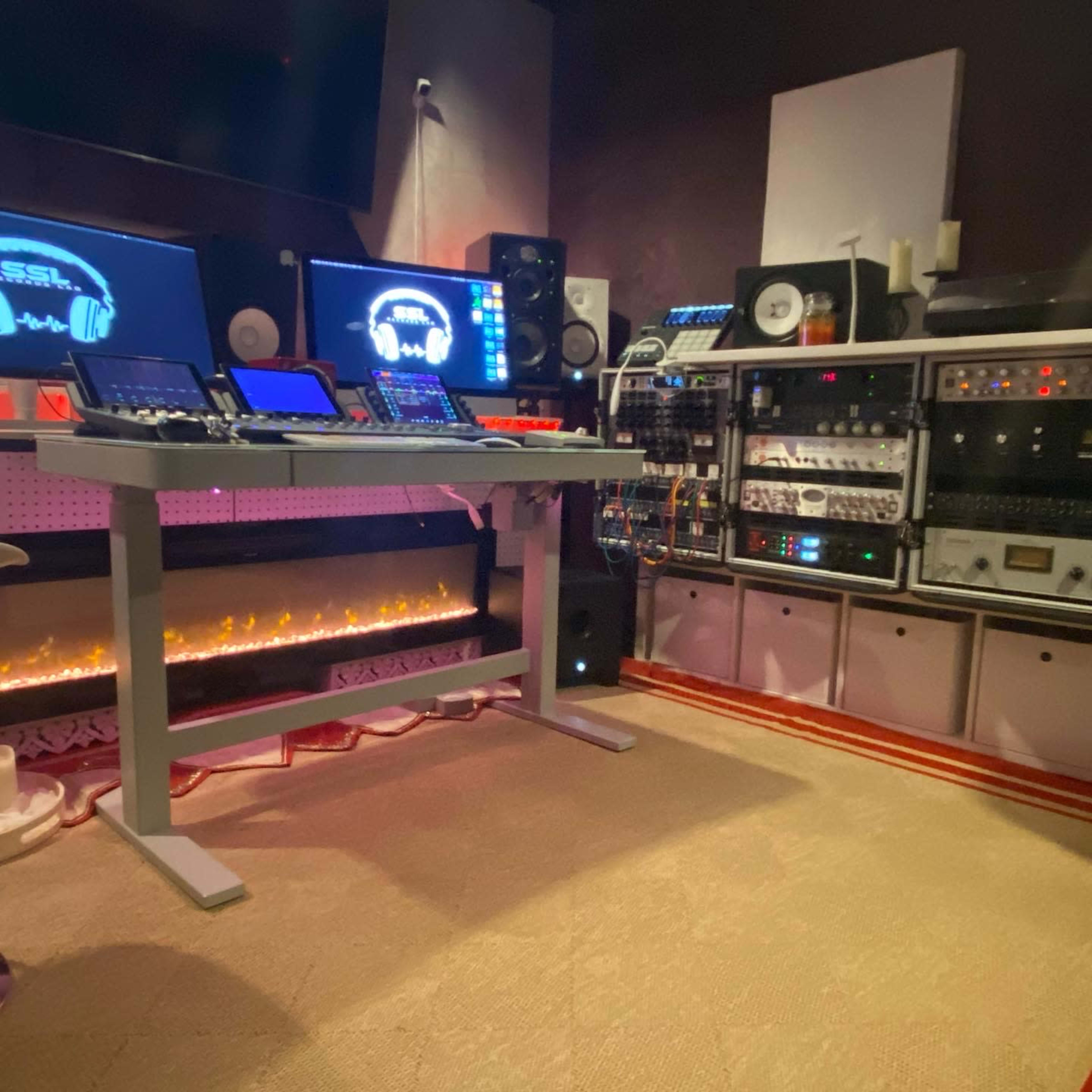A modern music production studio equipped with multiple screens, audio equipment, and a mixing desk.