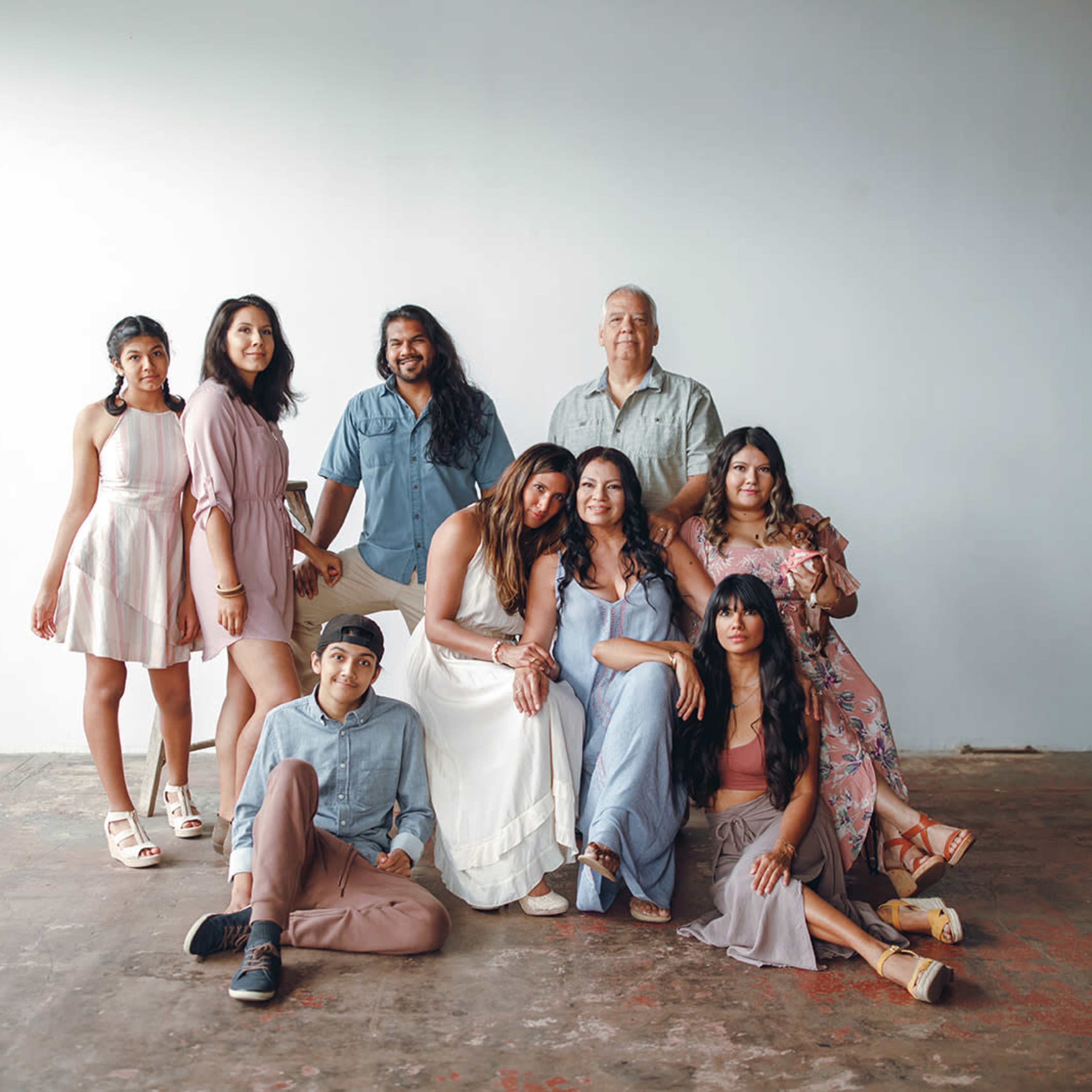 A group of nine people poses together in a bright, empty room with a concrete floor and neutral walls.