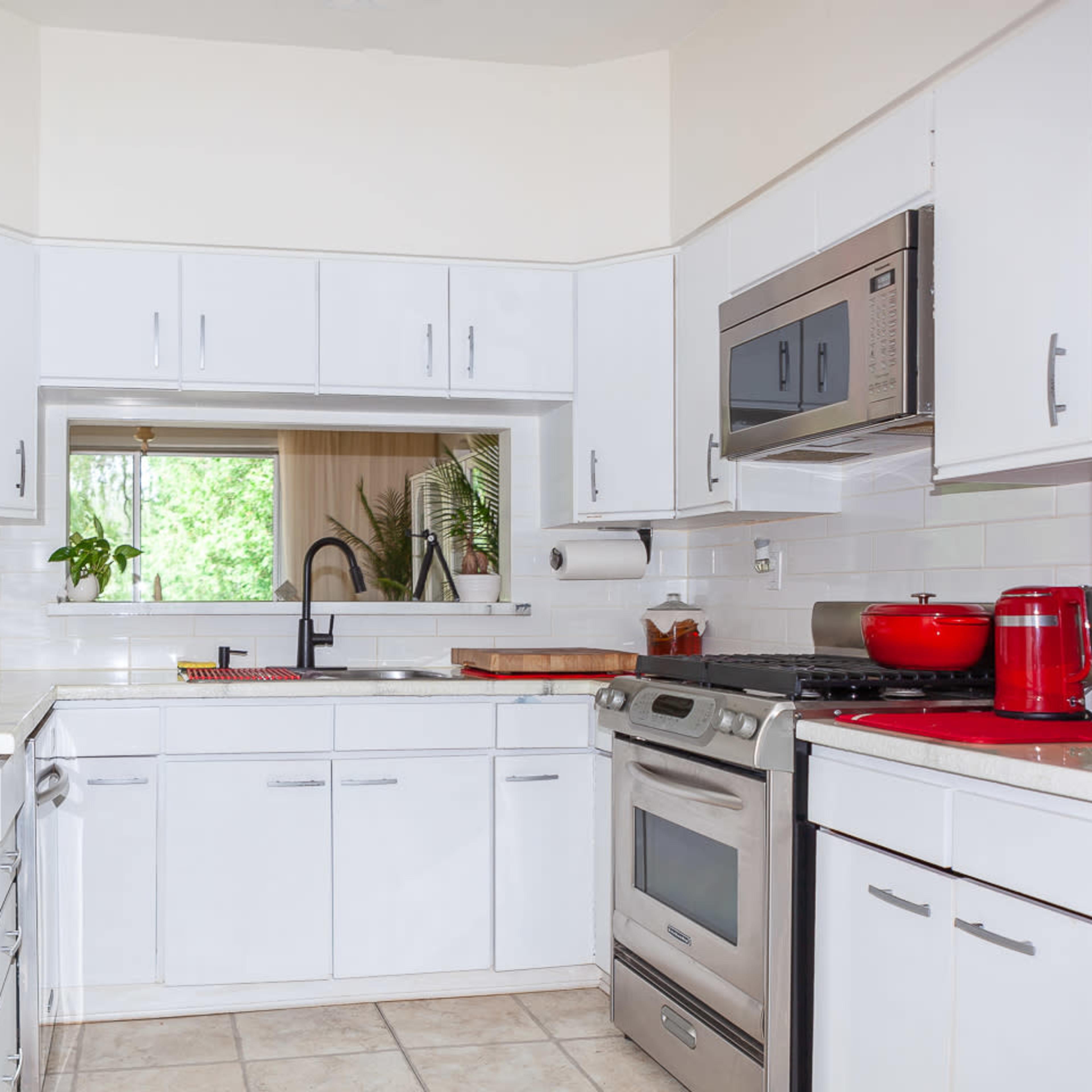 A modern kitchen with white cabinets, stainless steel appliances, and a tiled floor.