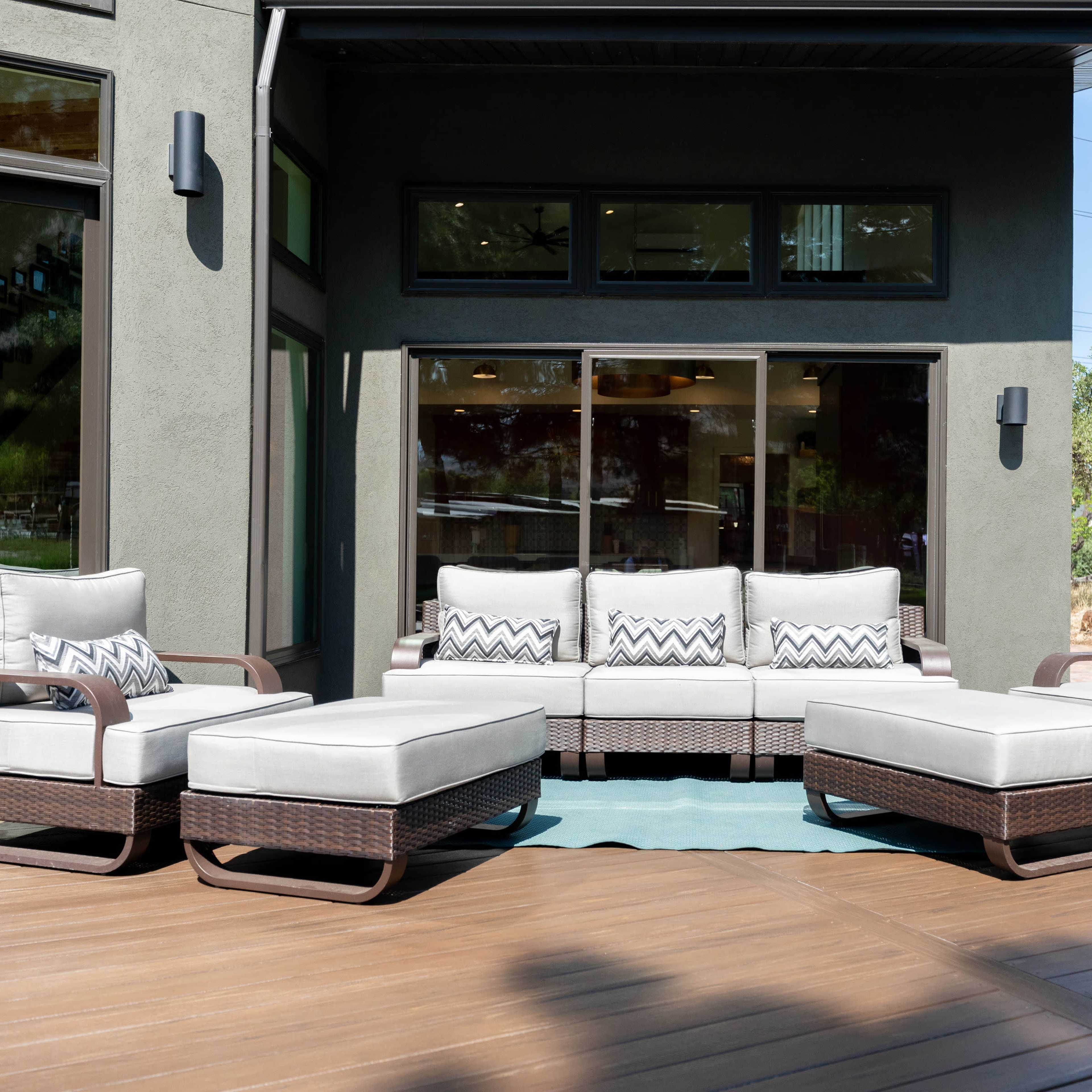 A modern outdoor seating area features a sectional couch and ottoman in a residential setting.