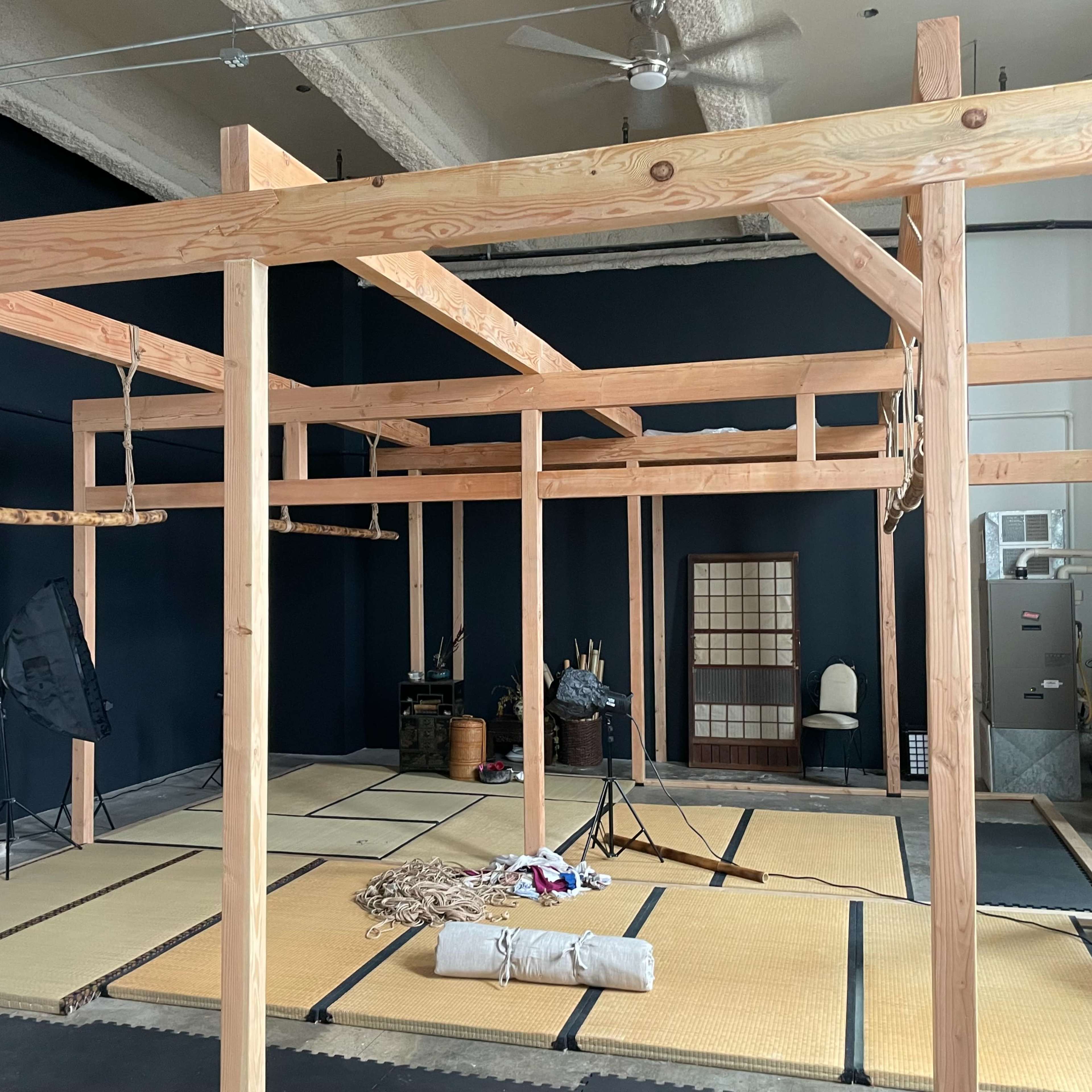 An empty interior space featuring a wooden structure with beams and tatami mats on the floor.