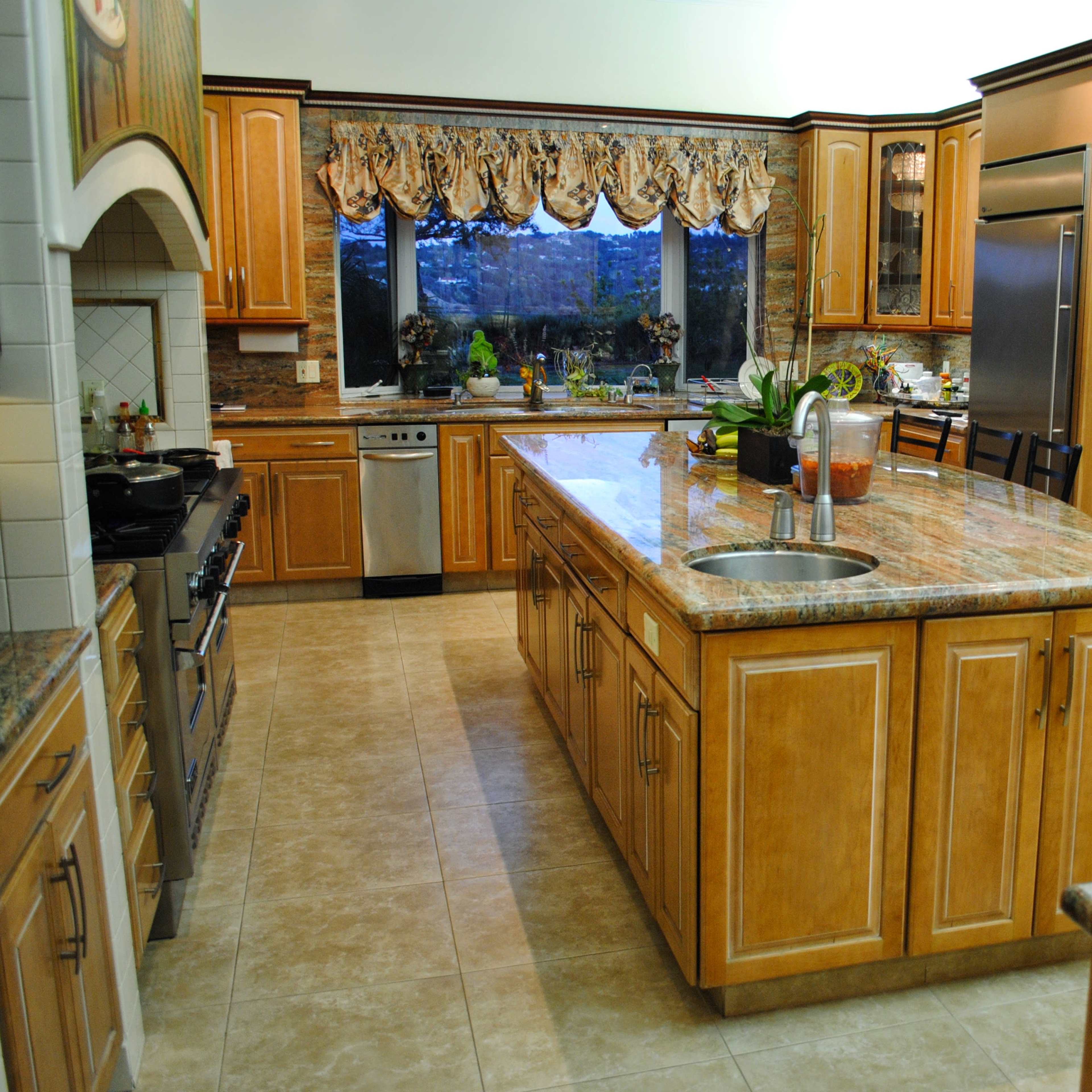 A spacious kitchen features wooden cabinets, a large central island with a sink, and stainless steel appliances.