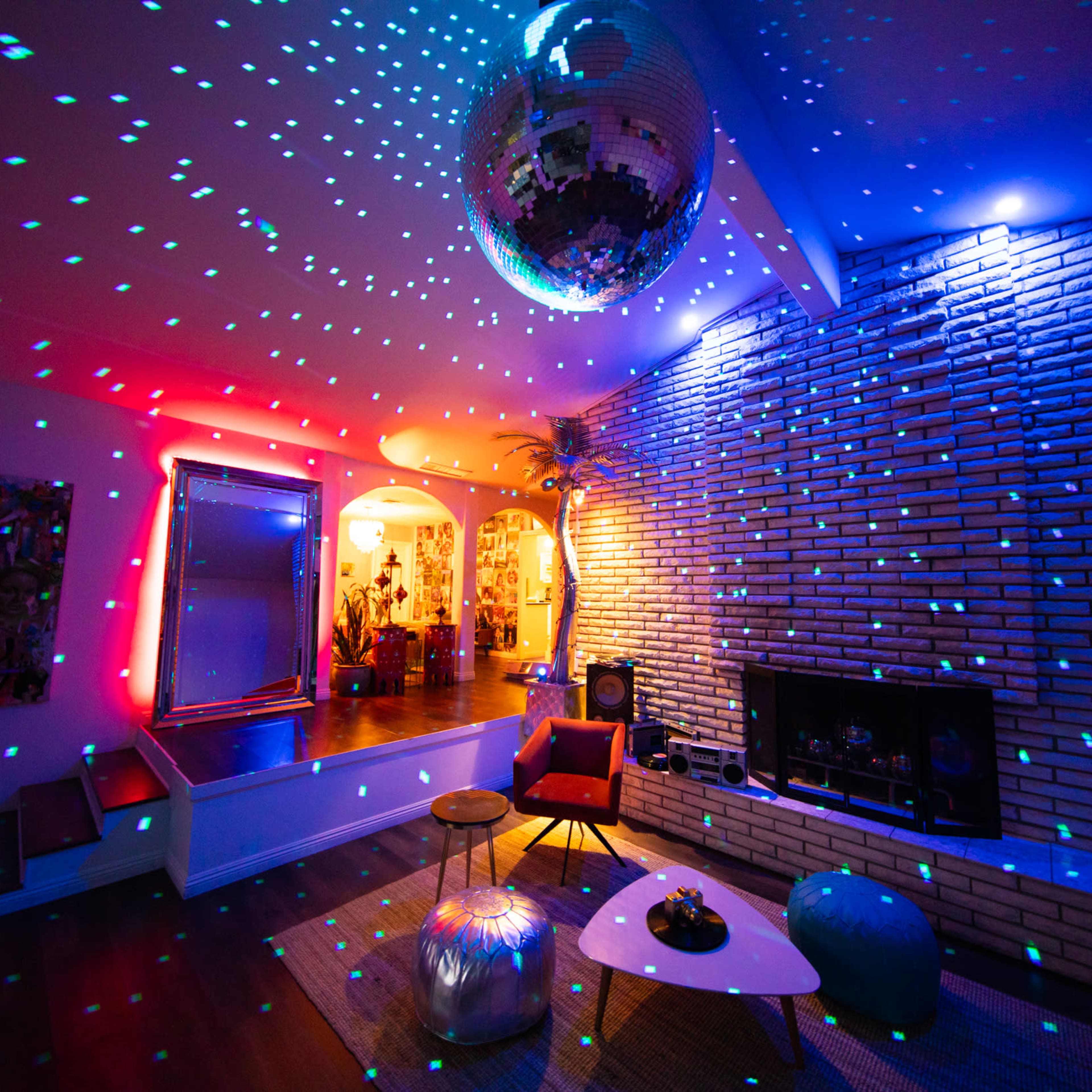 A modern living room with a disco ball reflecting colorful lights onto the walls and ceiling.